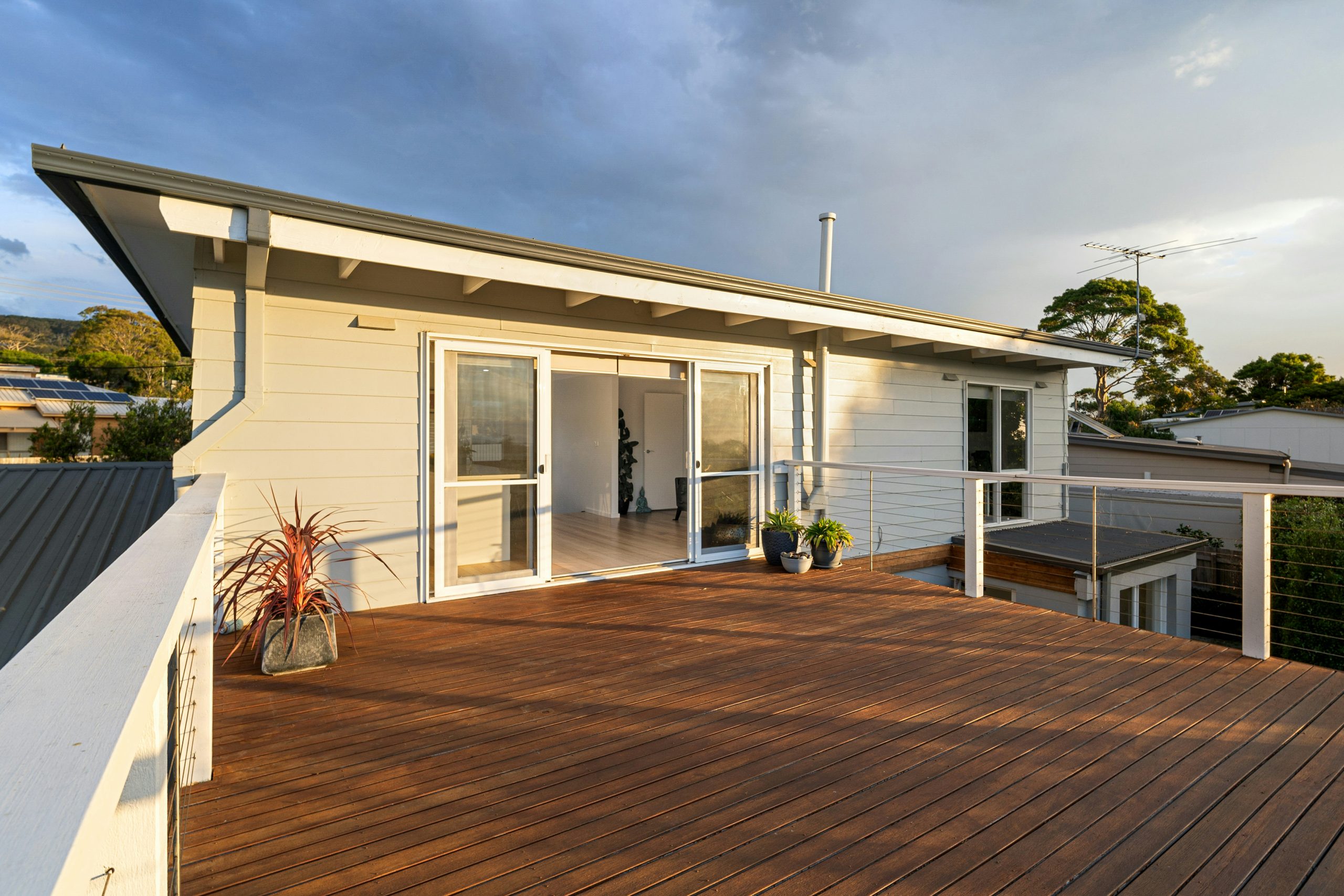 A wooden deck with a white house in the background