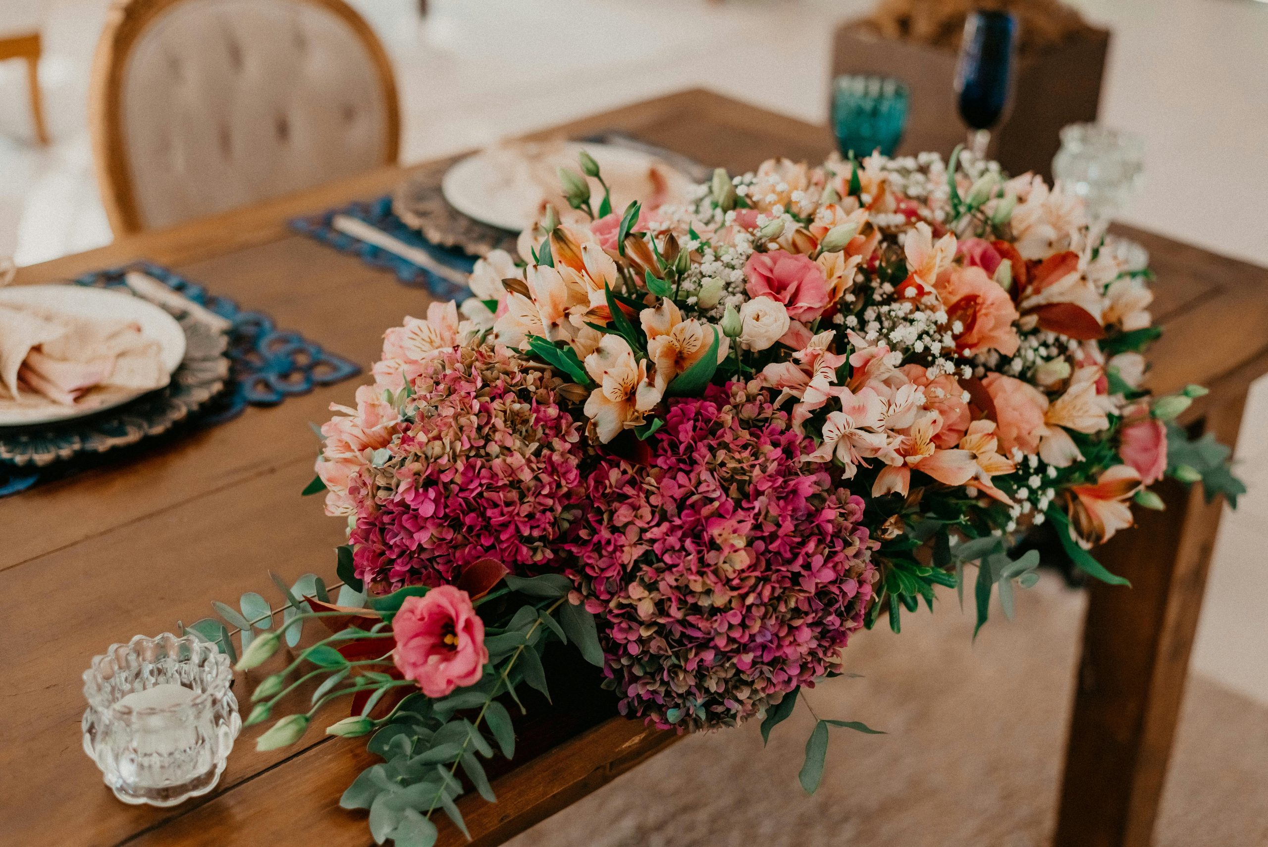 Beautiful floral centerpiece on a stylish wooden dining table setting indoors, ideal for celebrations.