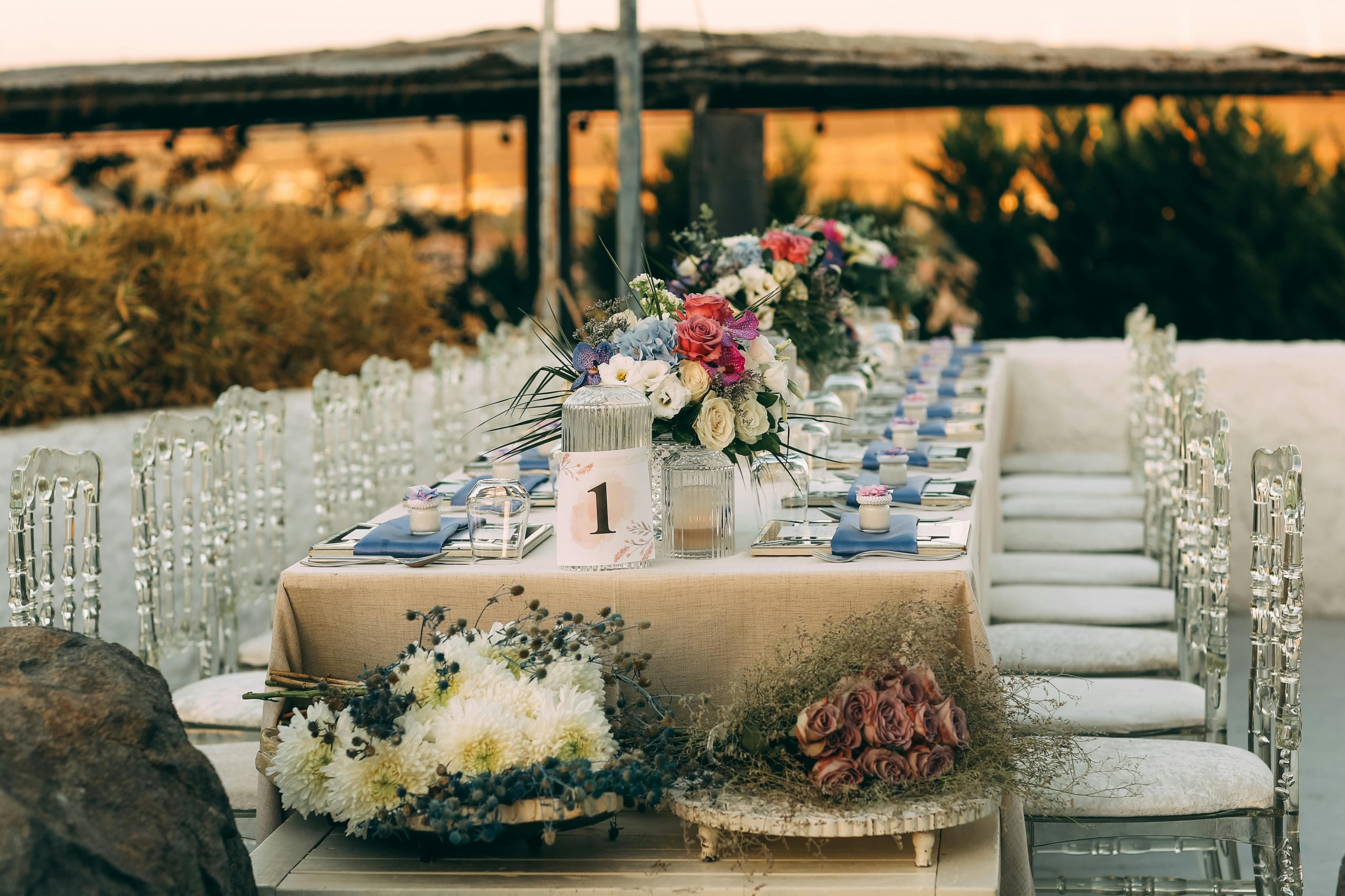Beautifully arranged outdoor wedding table with floral centerpiece under a warm sunset.