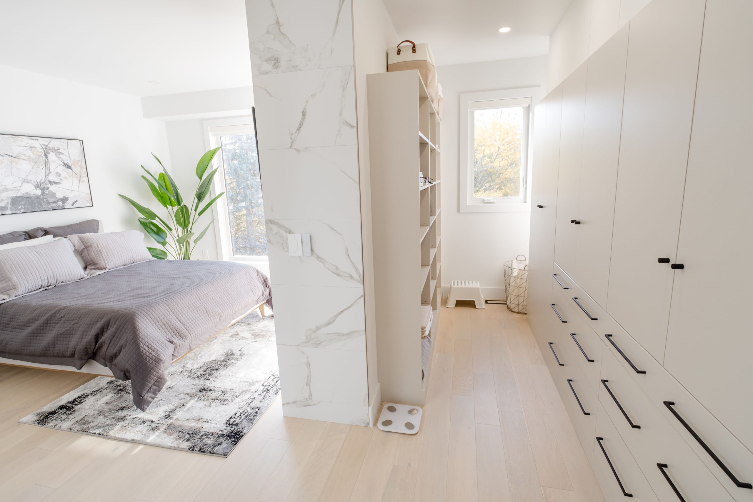 Bright and modern bedroom featuring a minimalist design with a walk-in closet and natural light.