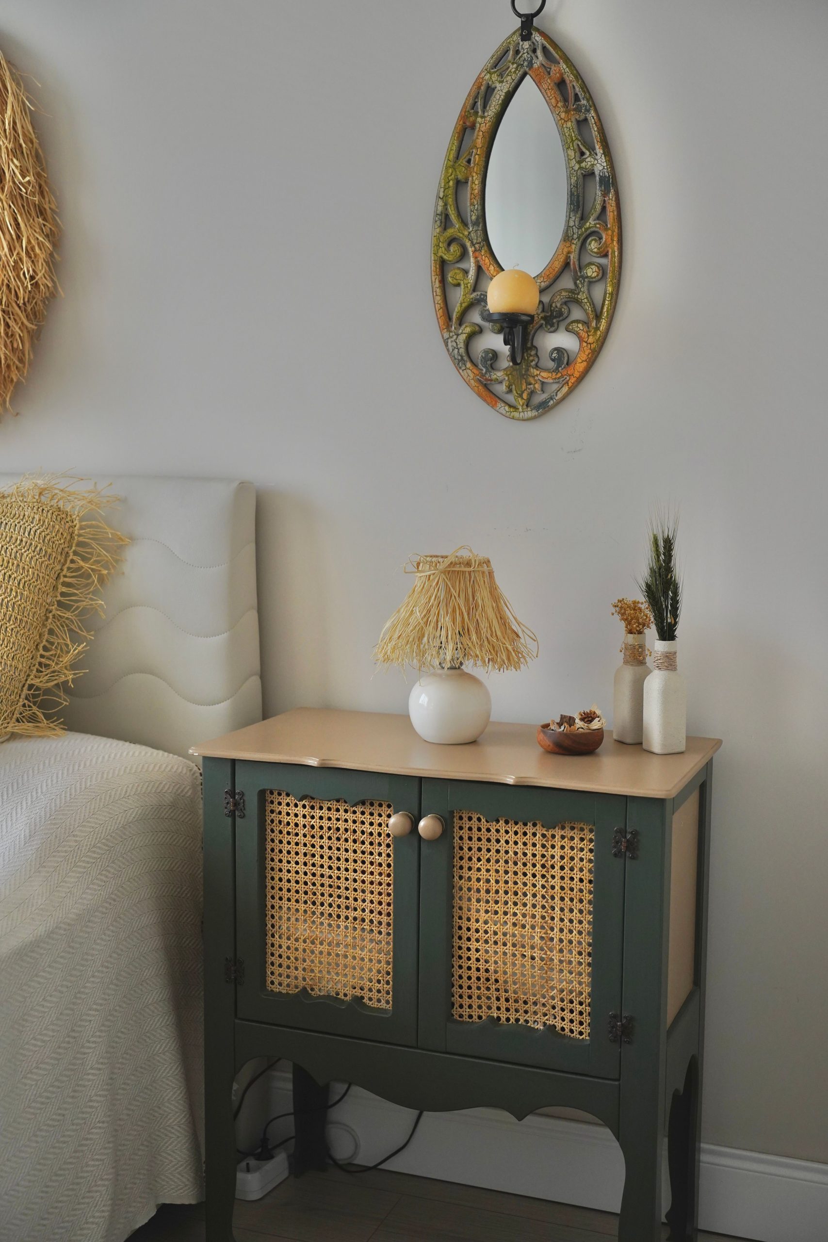 Chic bedroom interior featuring a stylish bedside table with a mirror above and decorative accents.