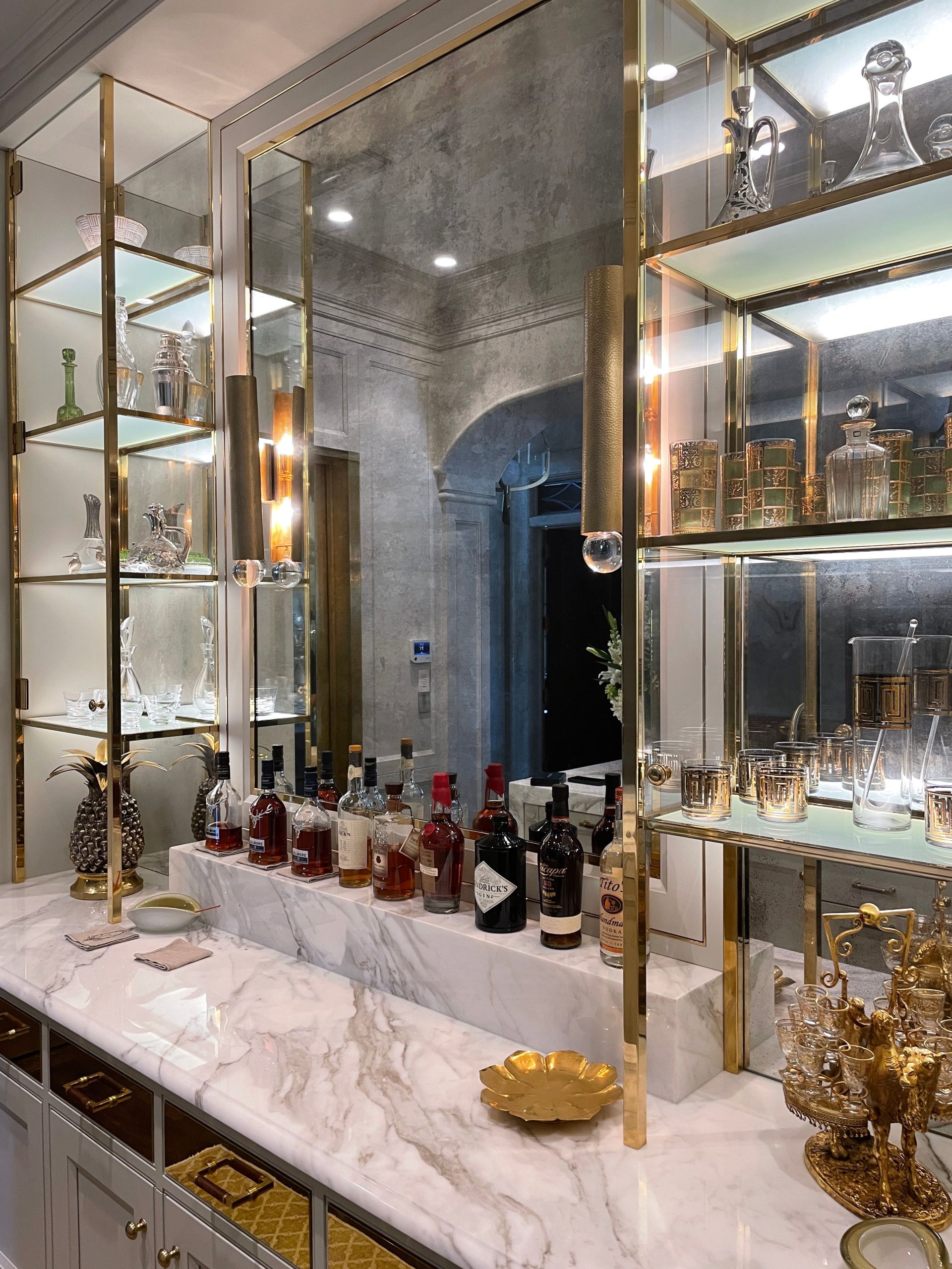 Chic home bar setup with marble top and elegant glassware on display shelves.