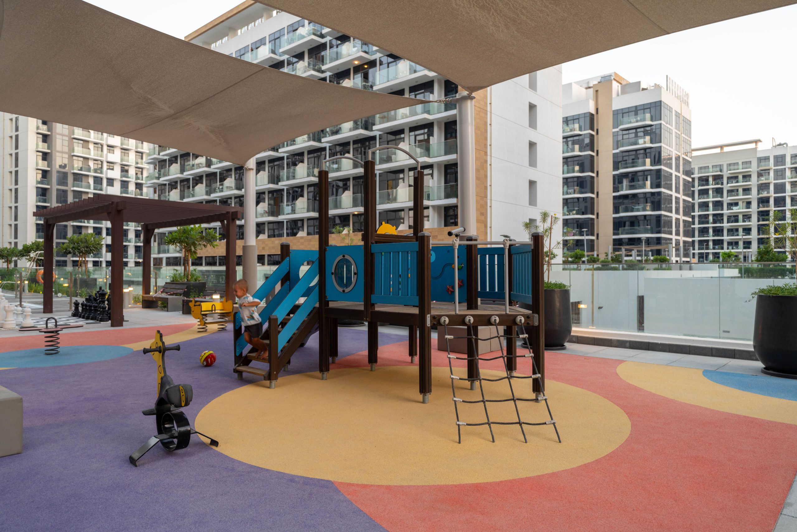 Colorful playground in a modern Dubai residential area with apartment buildings.