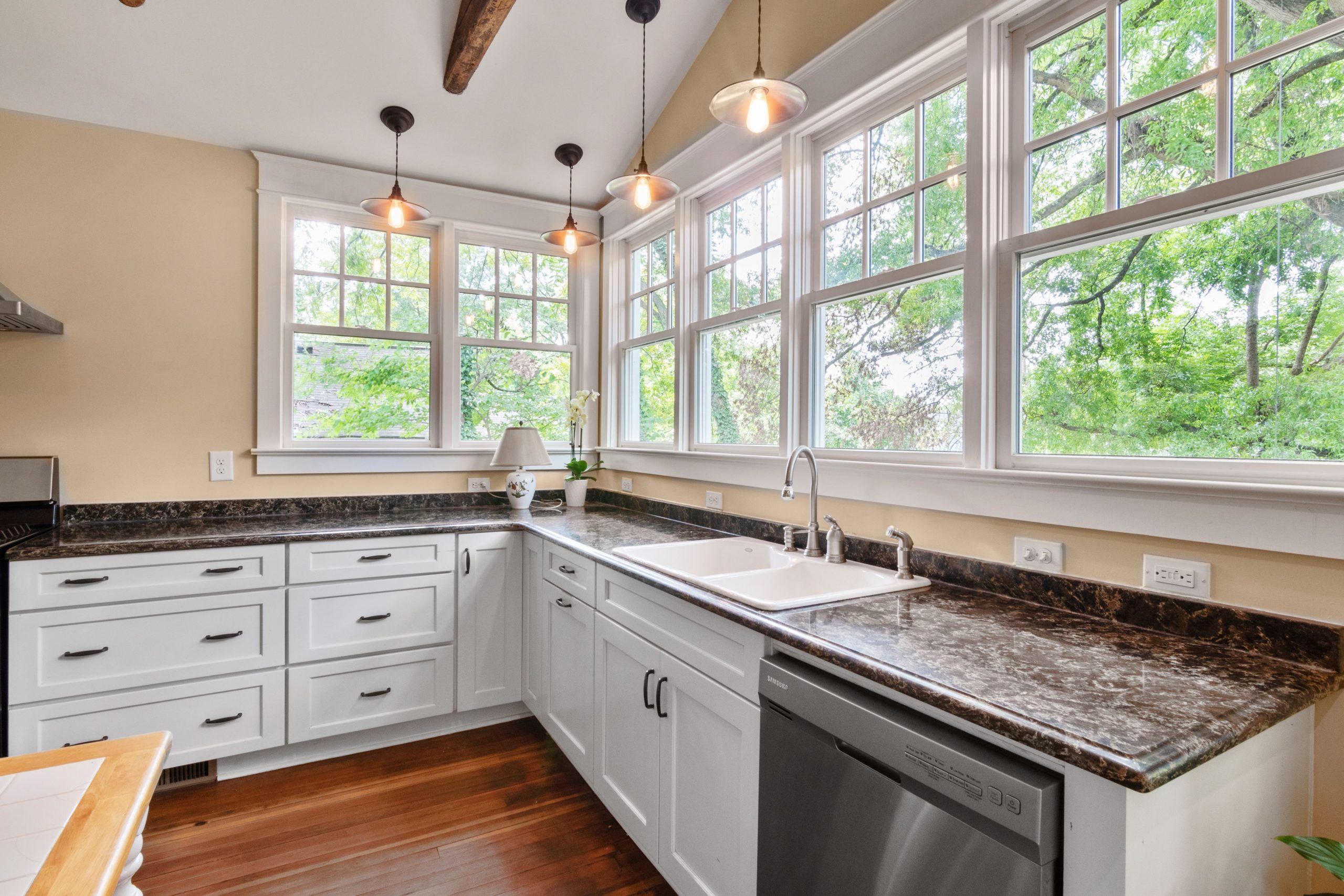 Contemporary kitchen design featuring big windows and sleek white cupboards.
