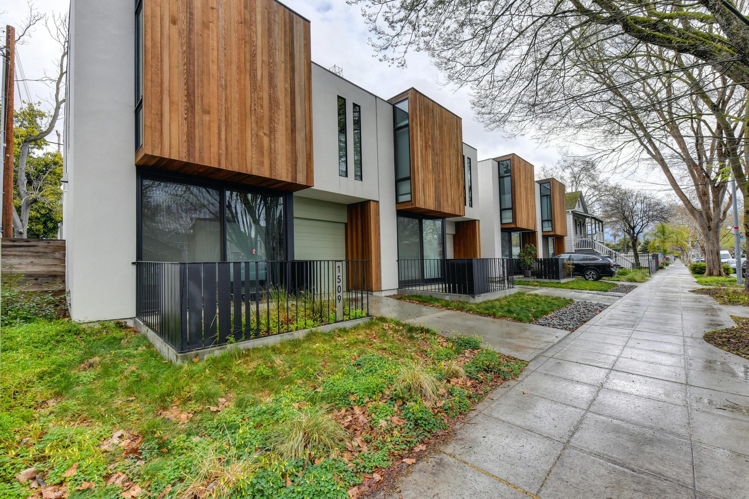 Contemporary suburban houses with wood accents in a tree-lined neighborhood.