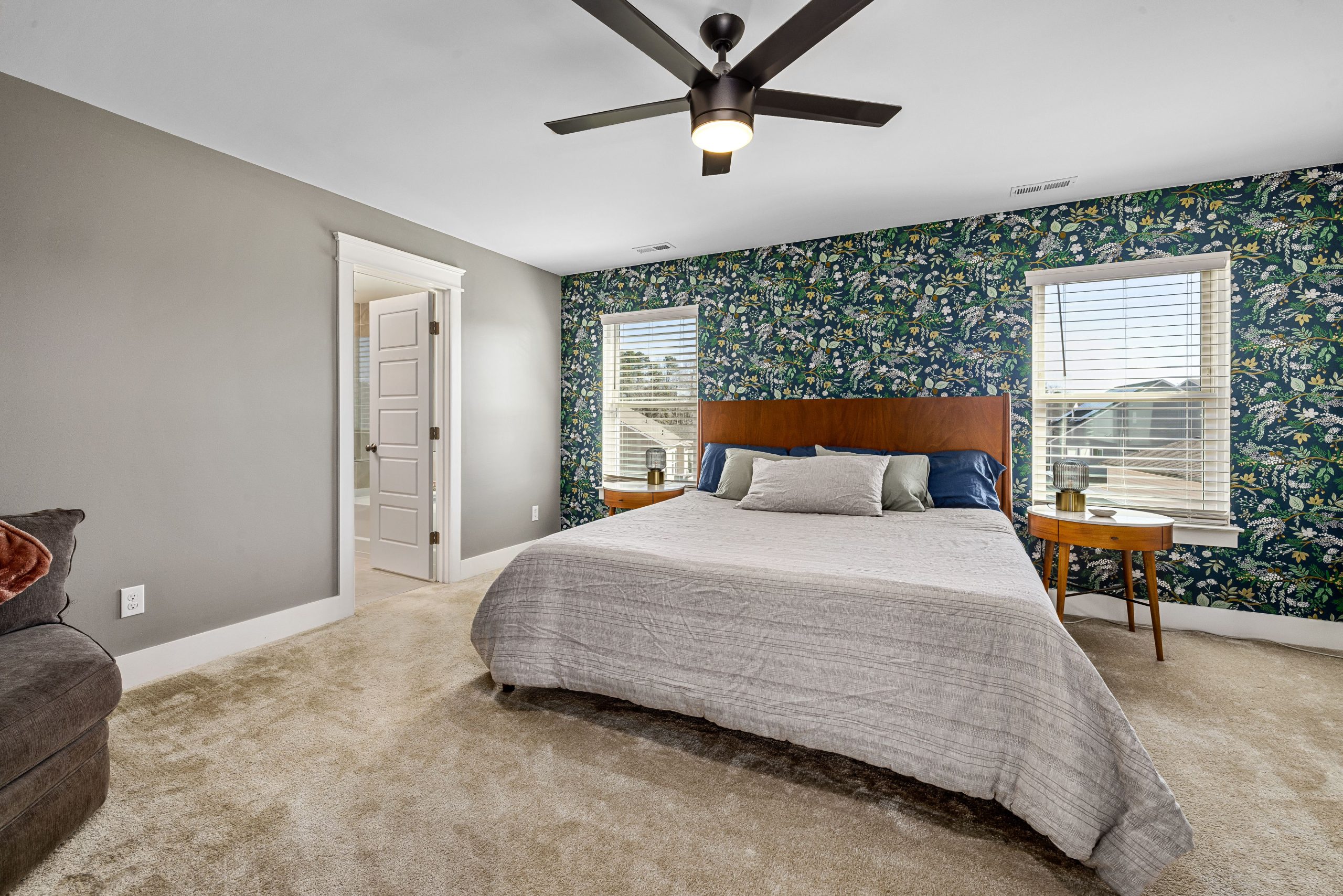 Cozy bedroom with a floral accent wall, double windows, and minimalist furniture, creating a serene and inviting atmosphere.
