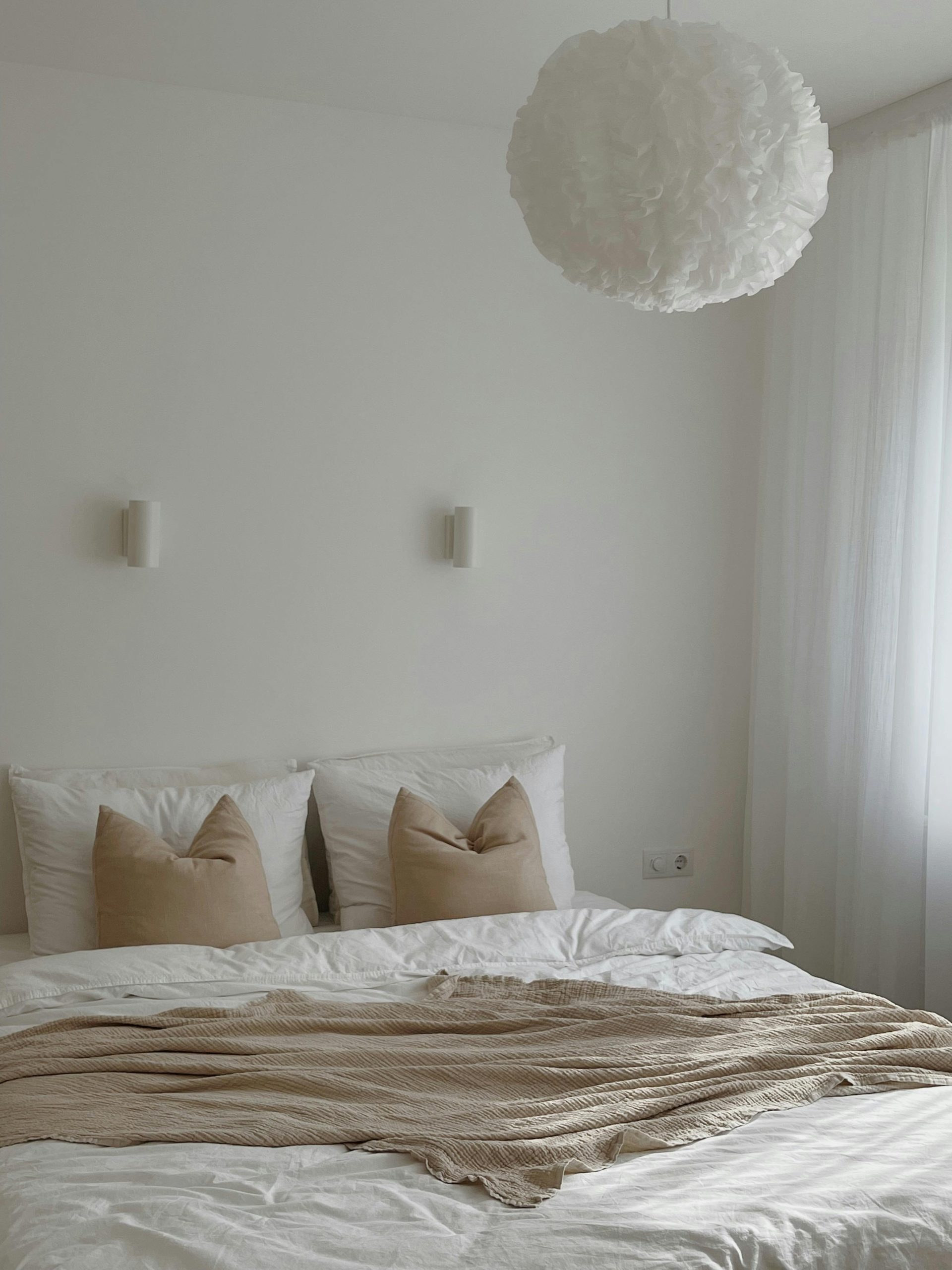 Cozy minimalist bedroom featuring neutral bedding and soft lighting.