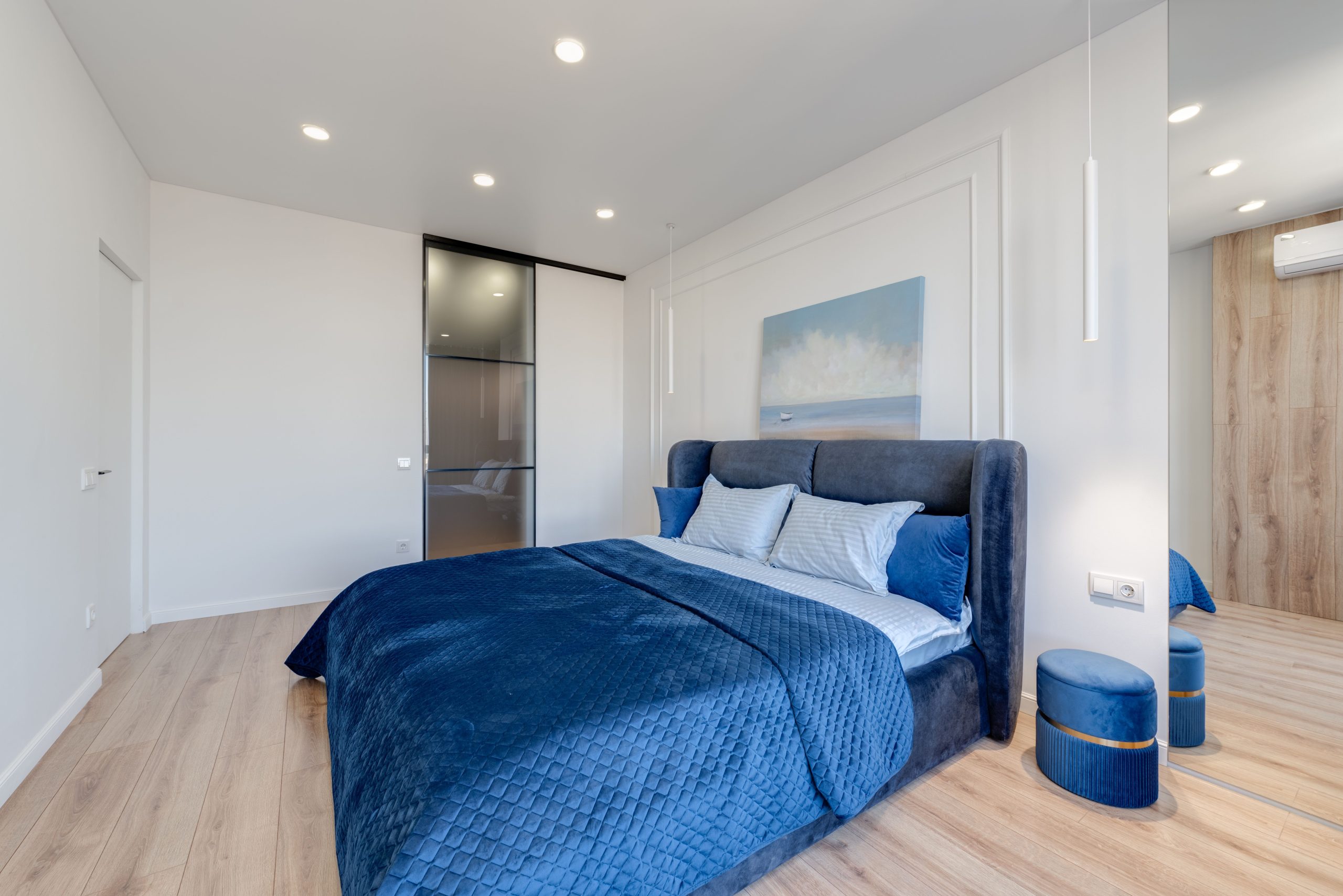 Cozy modern bedroom featuring a luxurious blue bed and stylish decor.