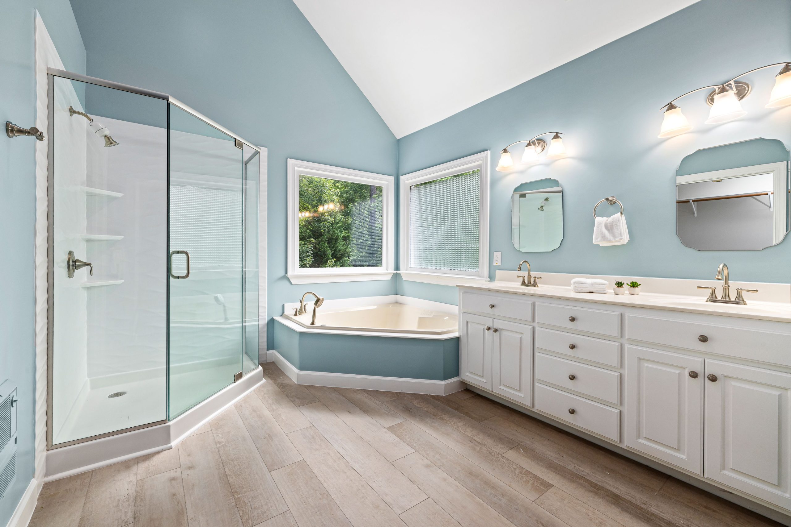 Elegant bathroom interior featuring a glass shower, bathtub, and dual sink vanity.