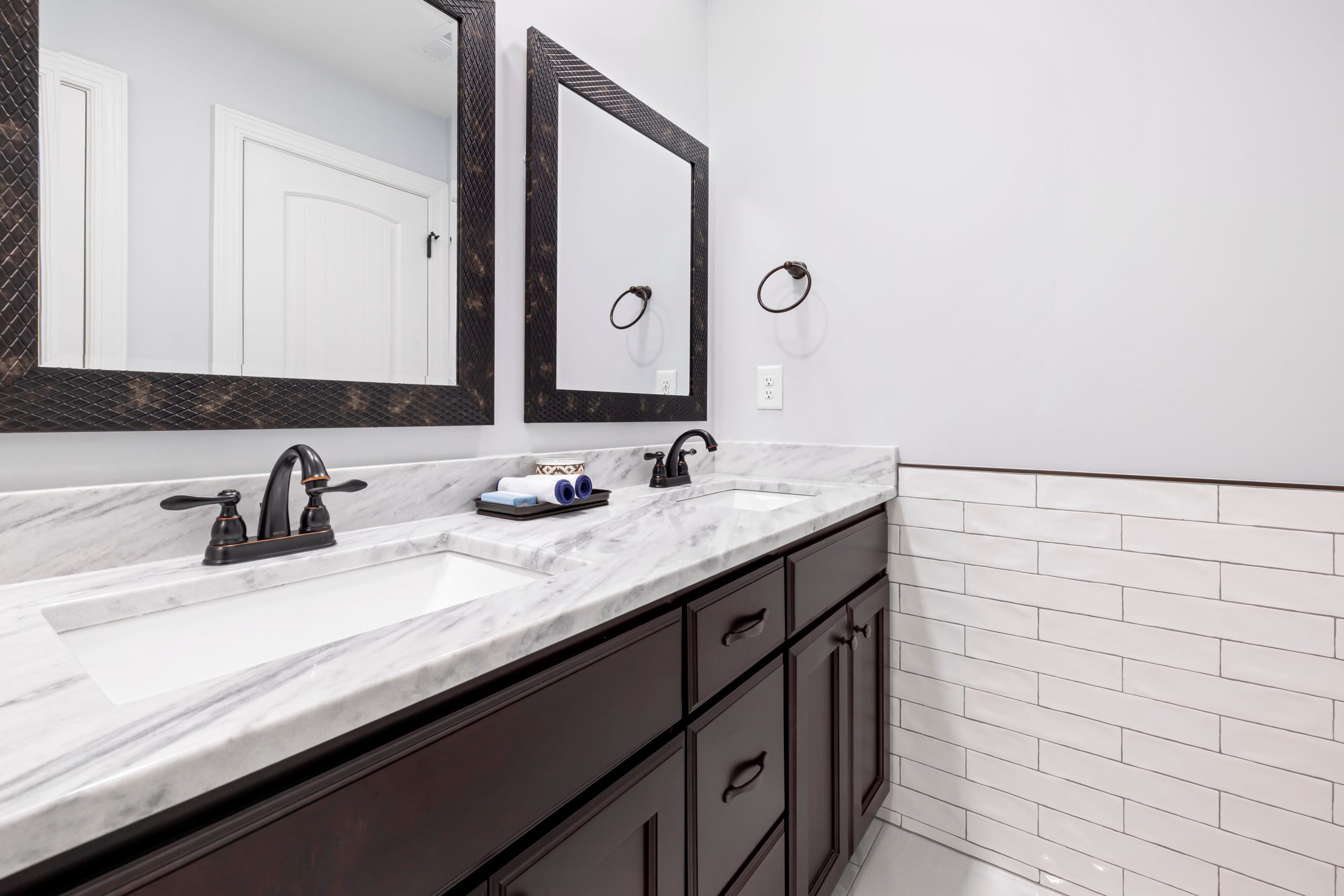 Elegant bathroom with dual sinks, marble countertop, and minimalist decor featuring dark wood cabinets.