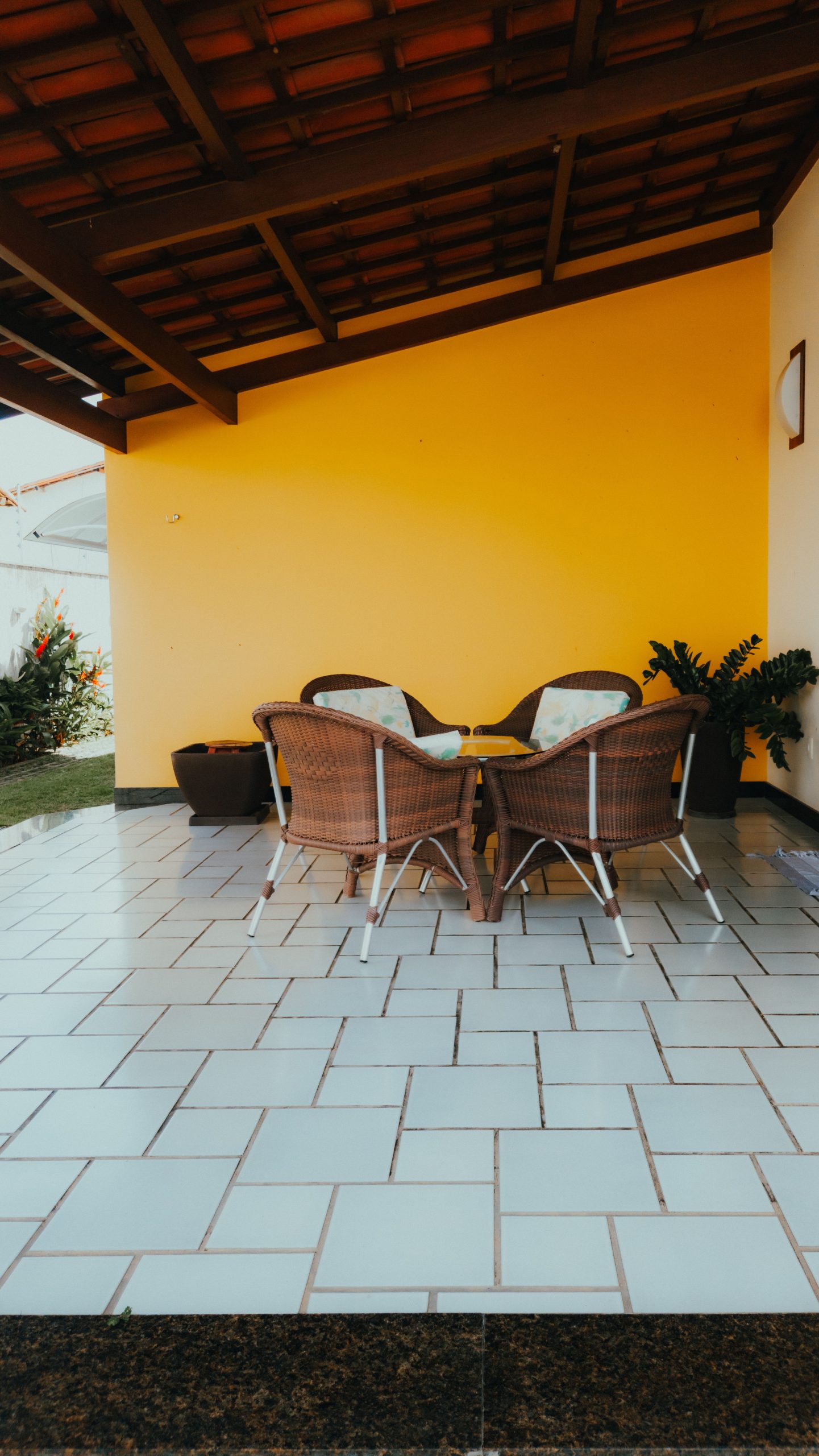 Inviting outdoor patio with rattan furniture set under a wooden roof, ideal for relaxation.