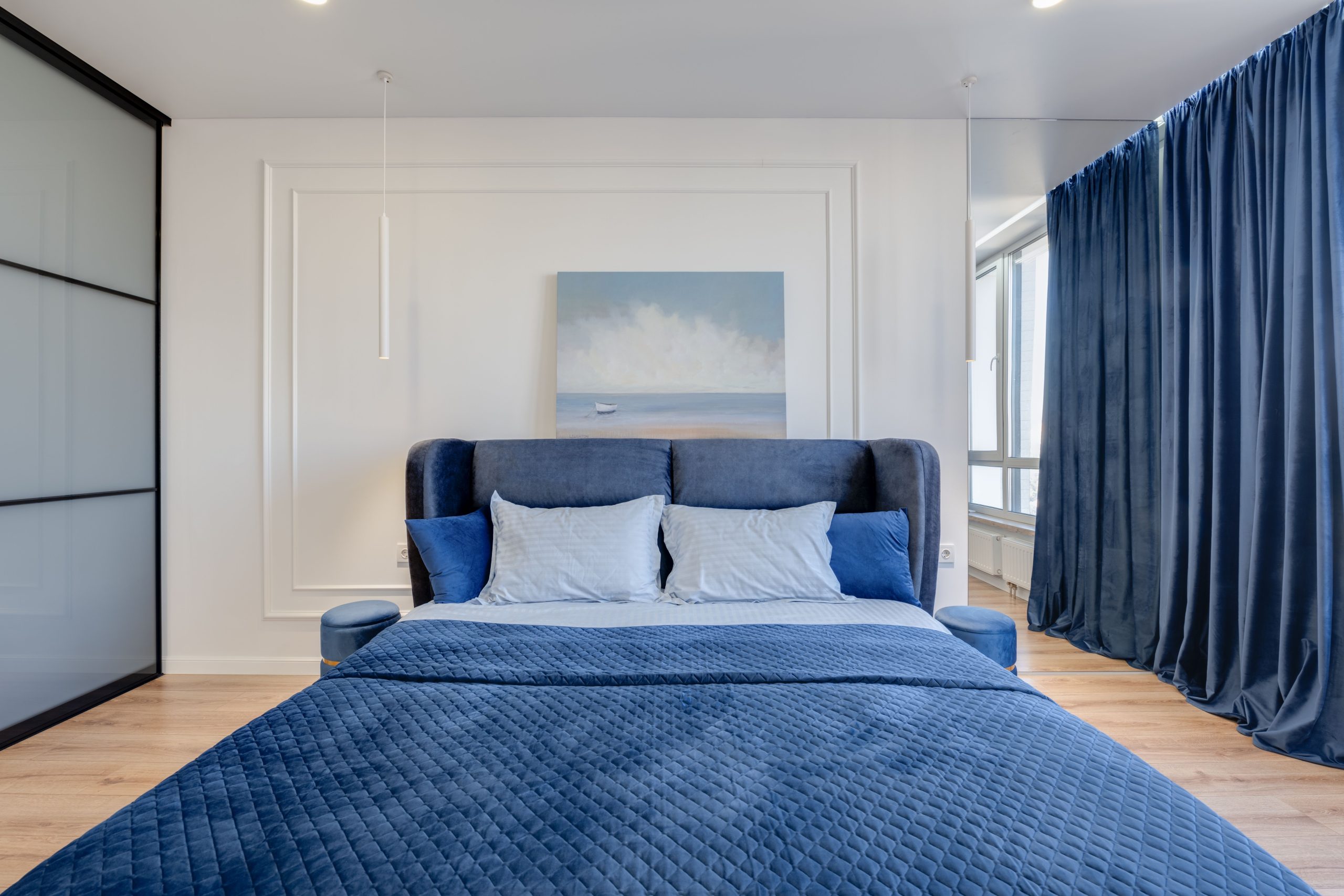 Luxurious bedroom with blue bedding, elegant decor, and natural light.