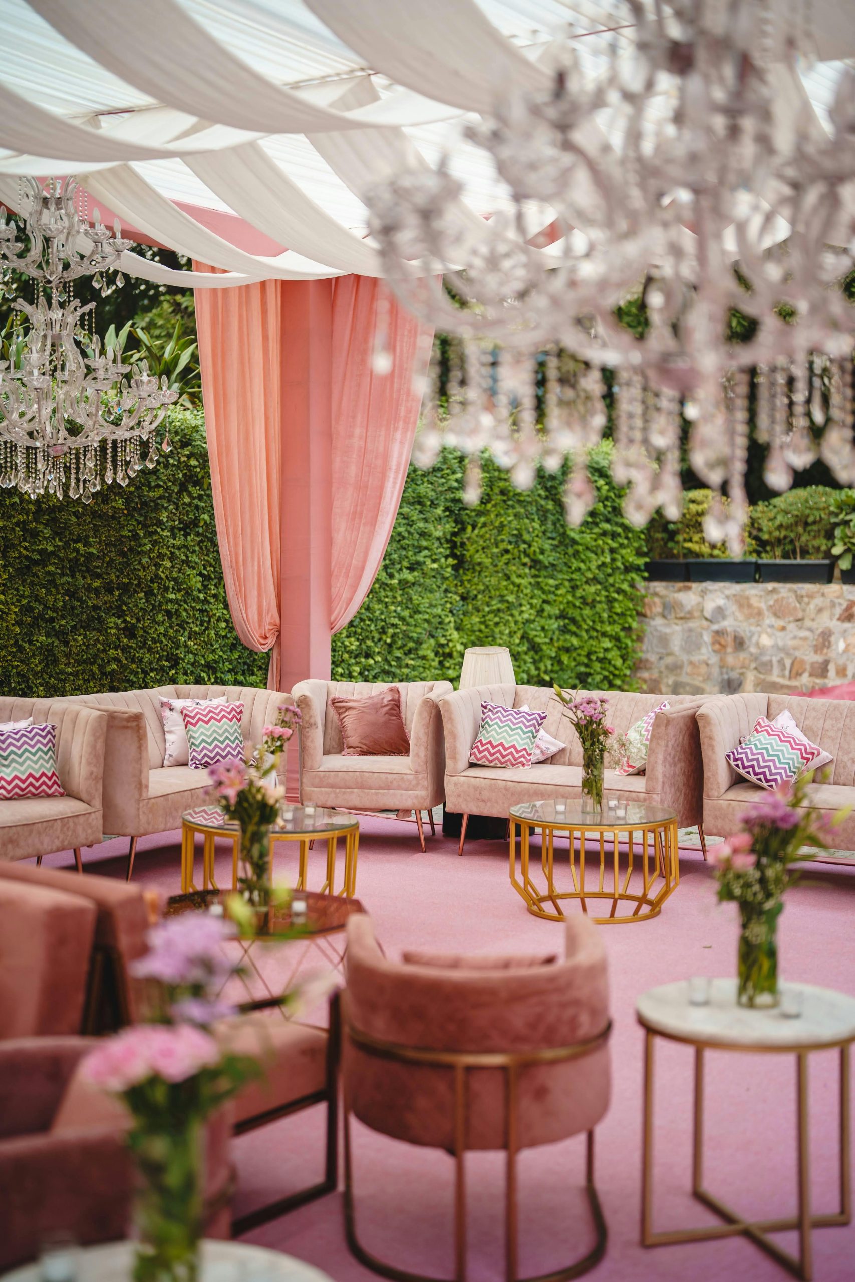 Luxurious pink garden lounge setup with plush seating and chandeliers, ideal for weddings and events.
