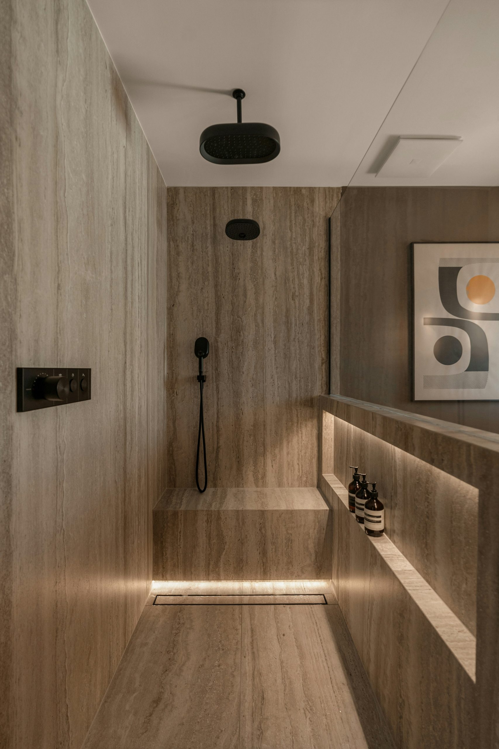 Luxury bathroom renovation with a stone vanity, floating cabinets, and walk-in shower. Soft ambient lighting and modern design create a high-end, minimalist aesthetic.