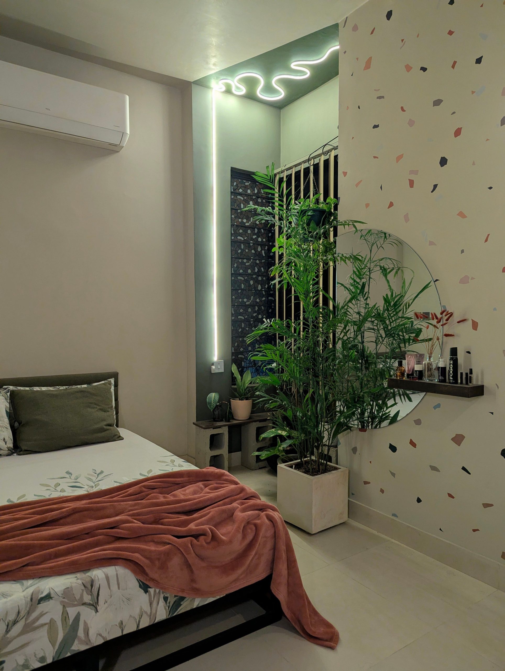 Modern bedroom featuring terrazzo wall, indoor plants, and ambient lighting for a cozy atmosphere.