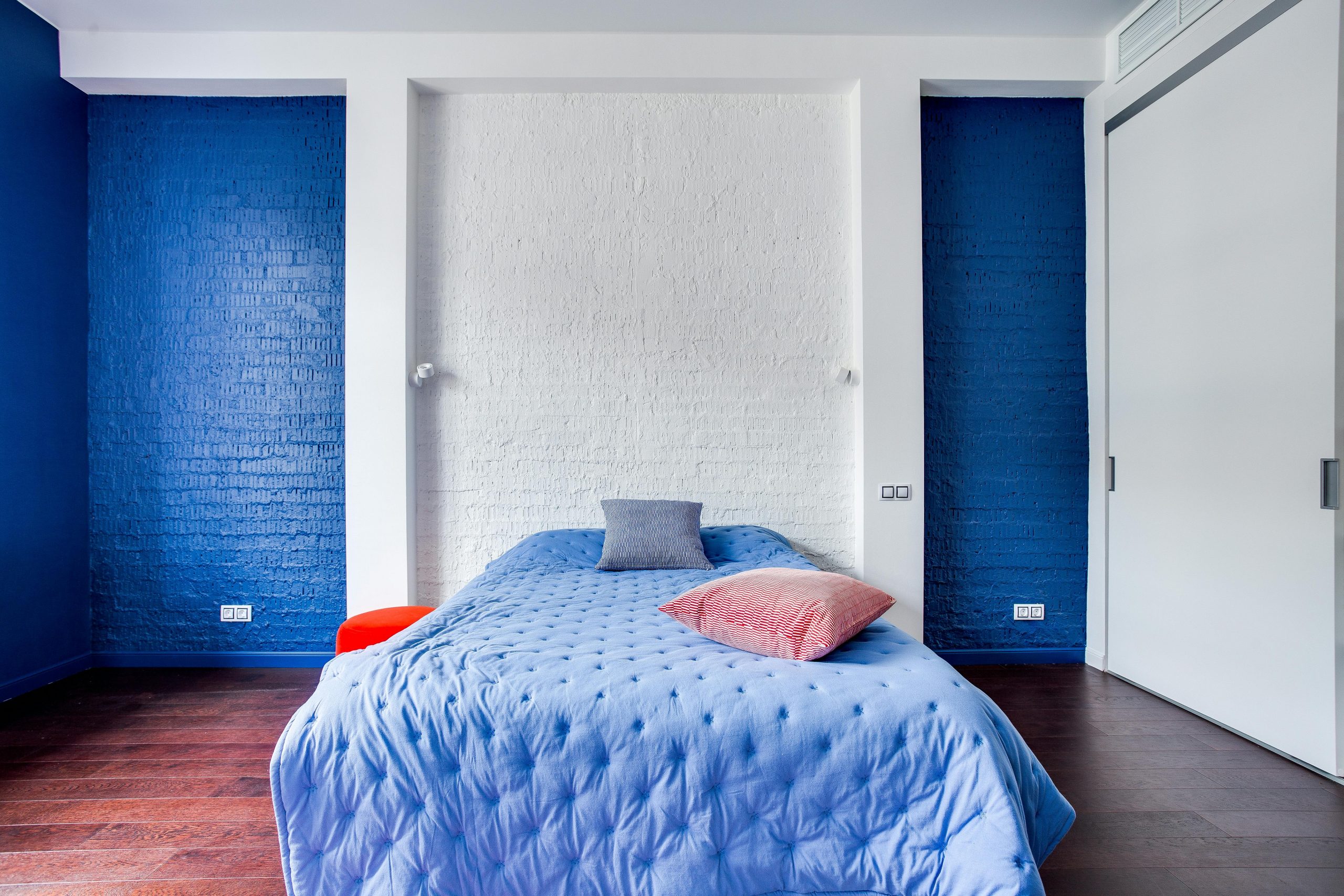 Modern bedroom with navy blue walls, cozy bed, and stylish pillows.
