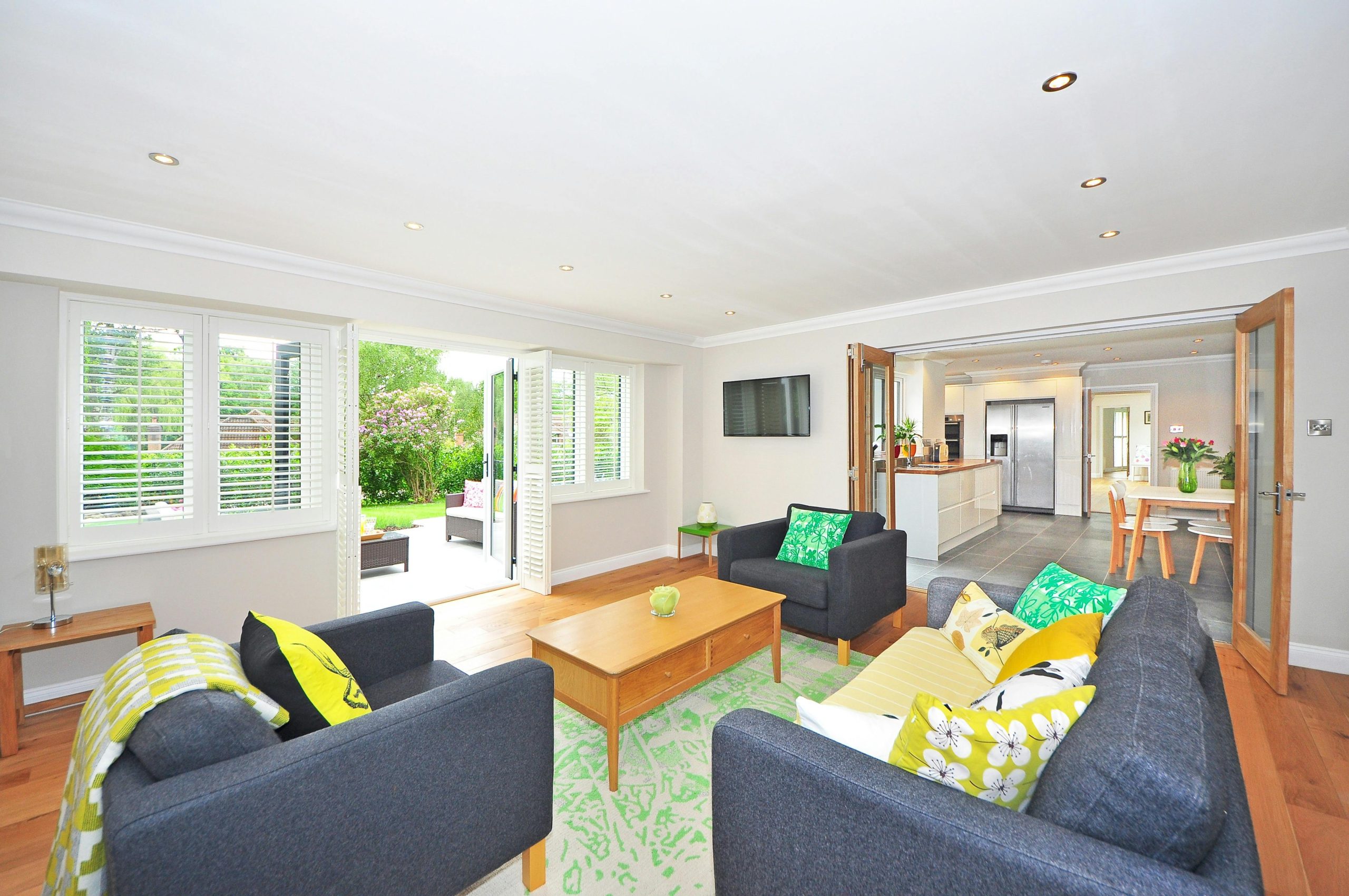 Modern living room with open plan kitchen and garden view, bright and airy ambiance.