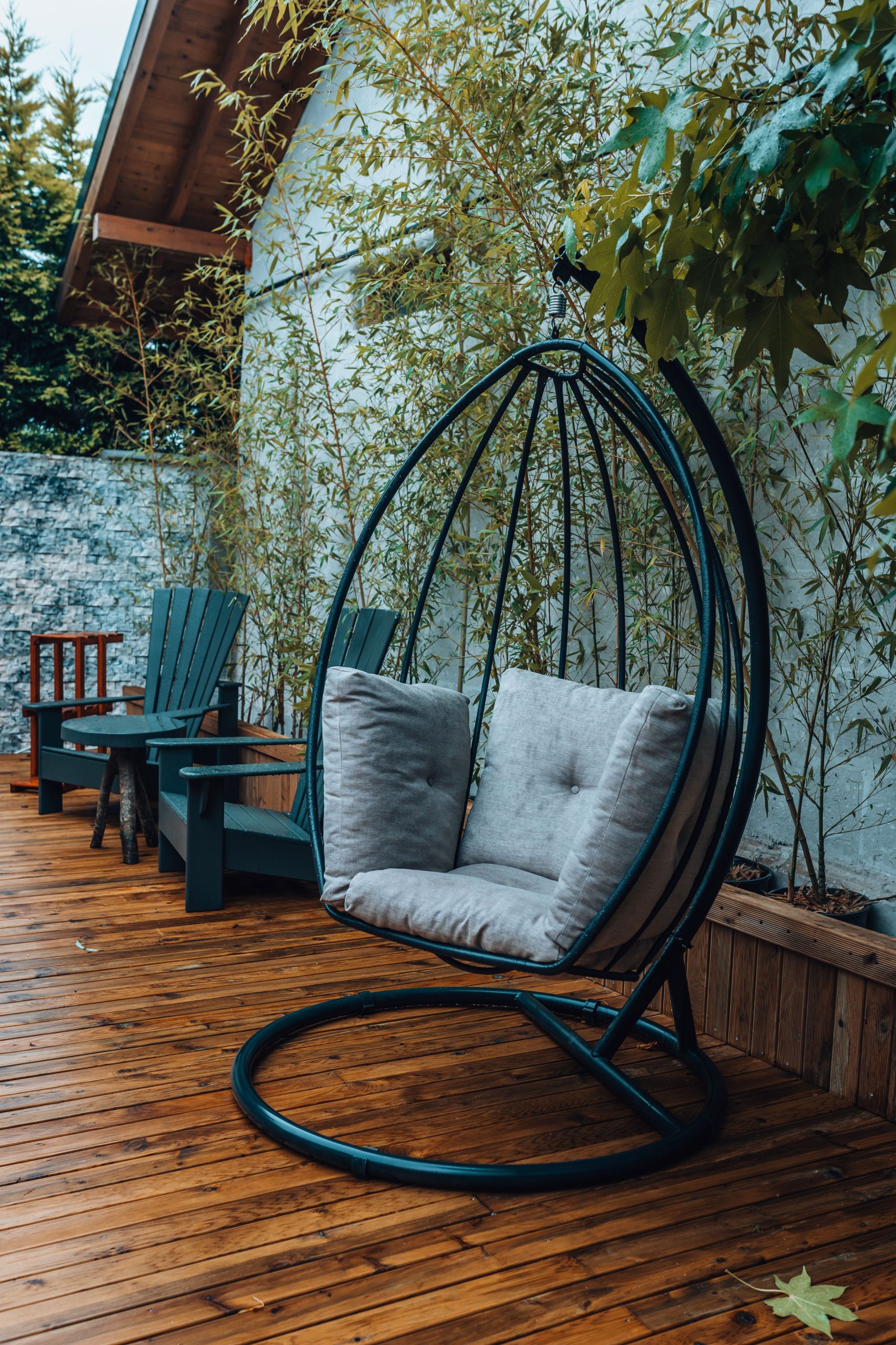 Rustic outdoor patio featuring a hanging swing chair, cozy seating, and lush greenery.