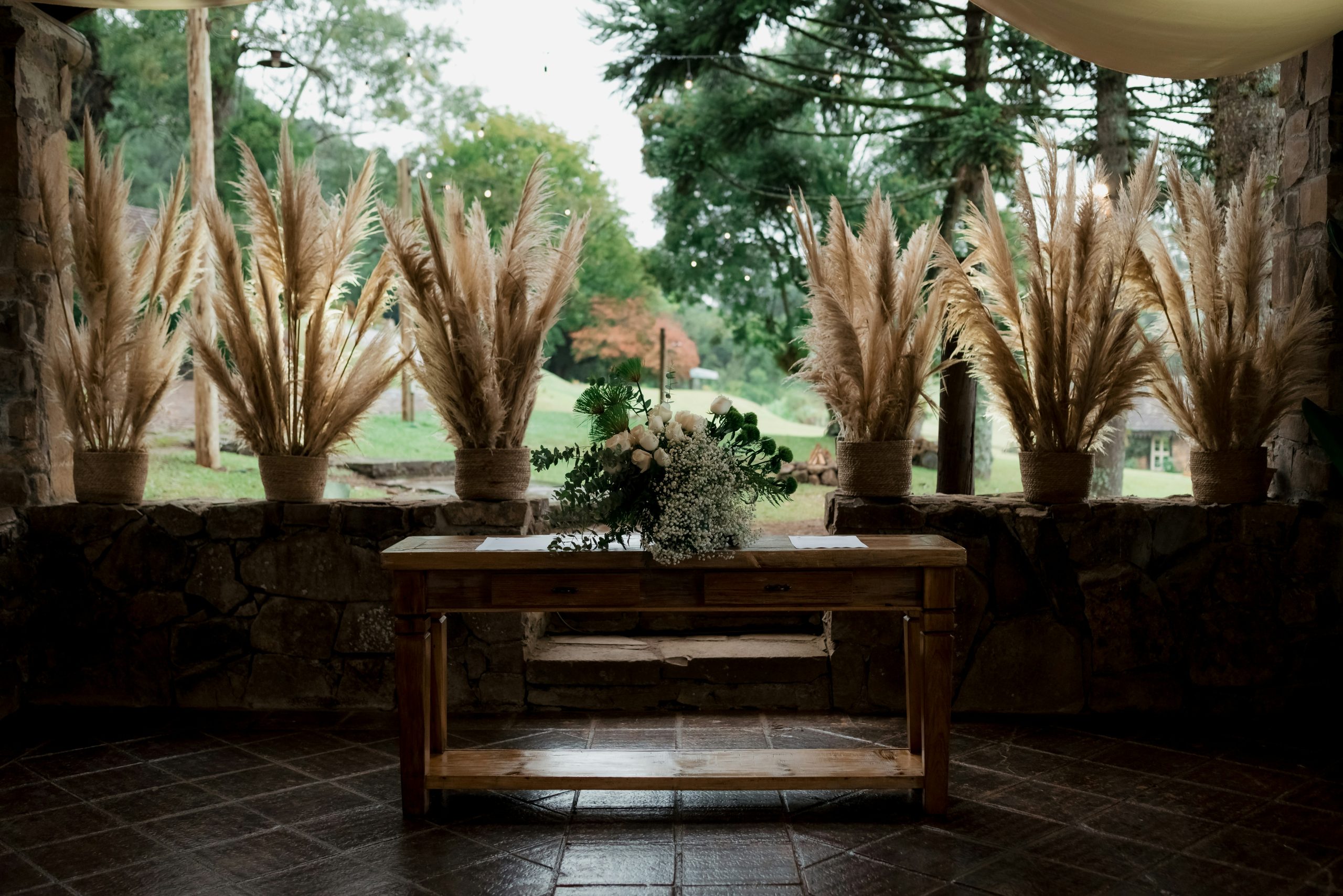 Rustic wooden table with floral arrangement and pampas grass.
