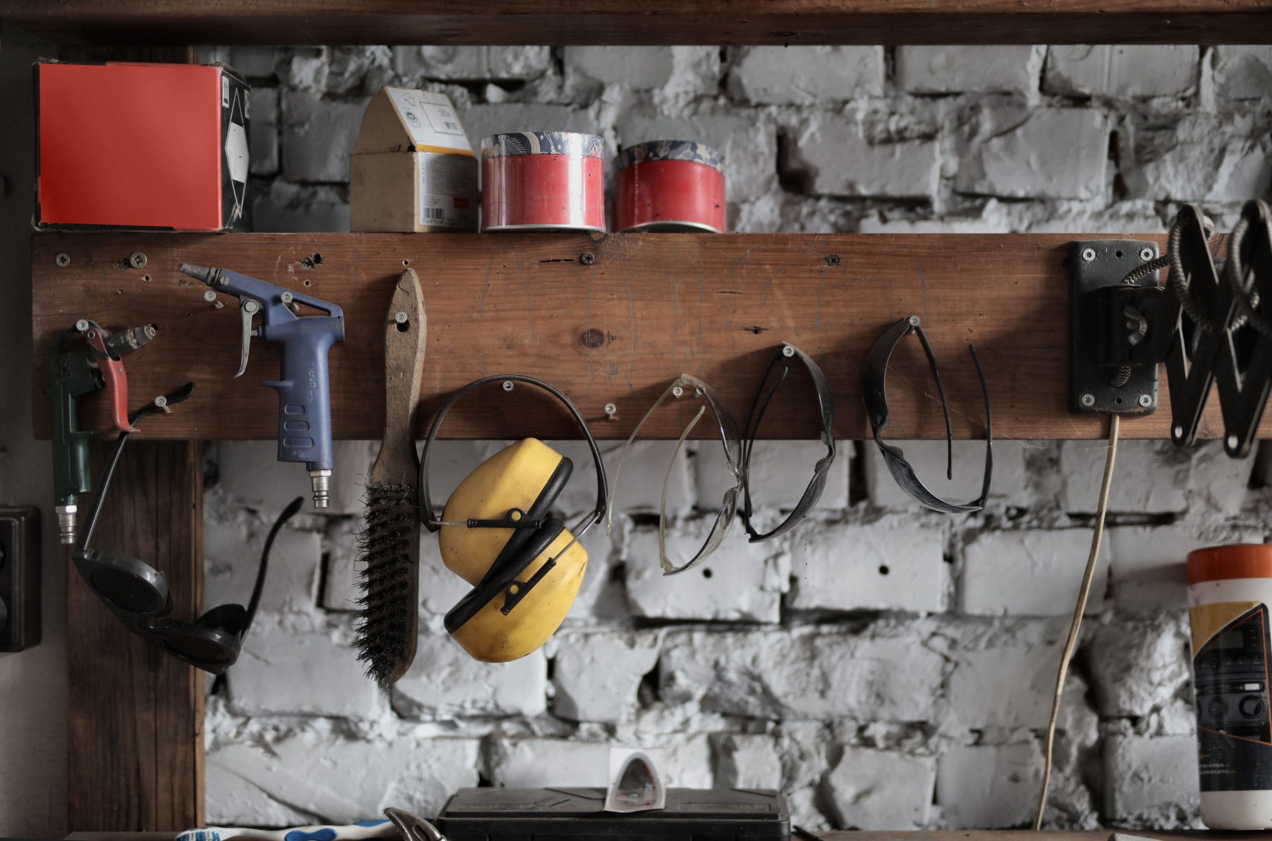 Set of various tools placed on wooden board near brick wall in workshop