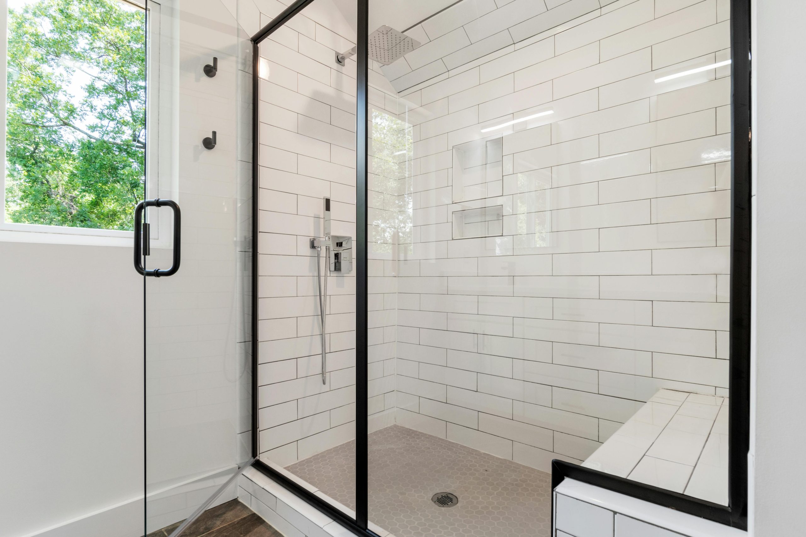 Sleek and modern shower with glass panels and tiled walls in a bright bathroom.