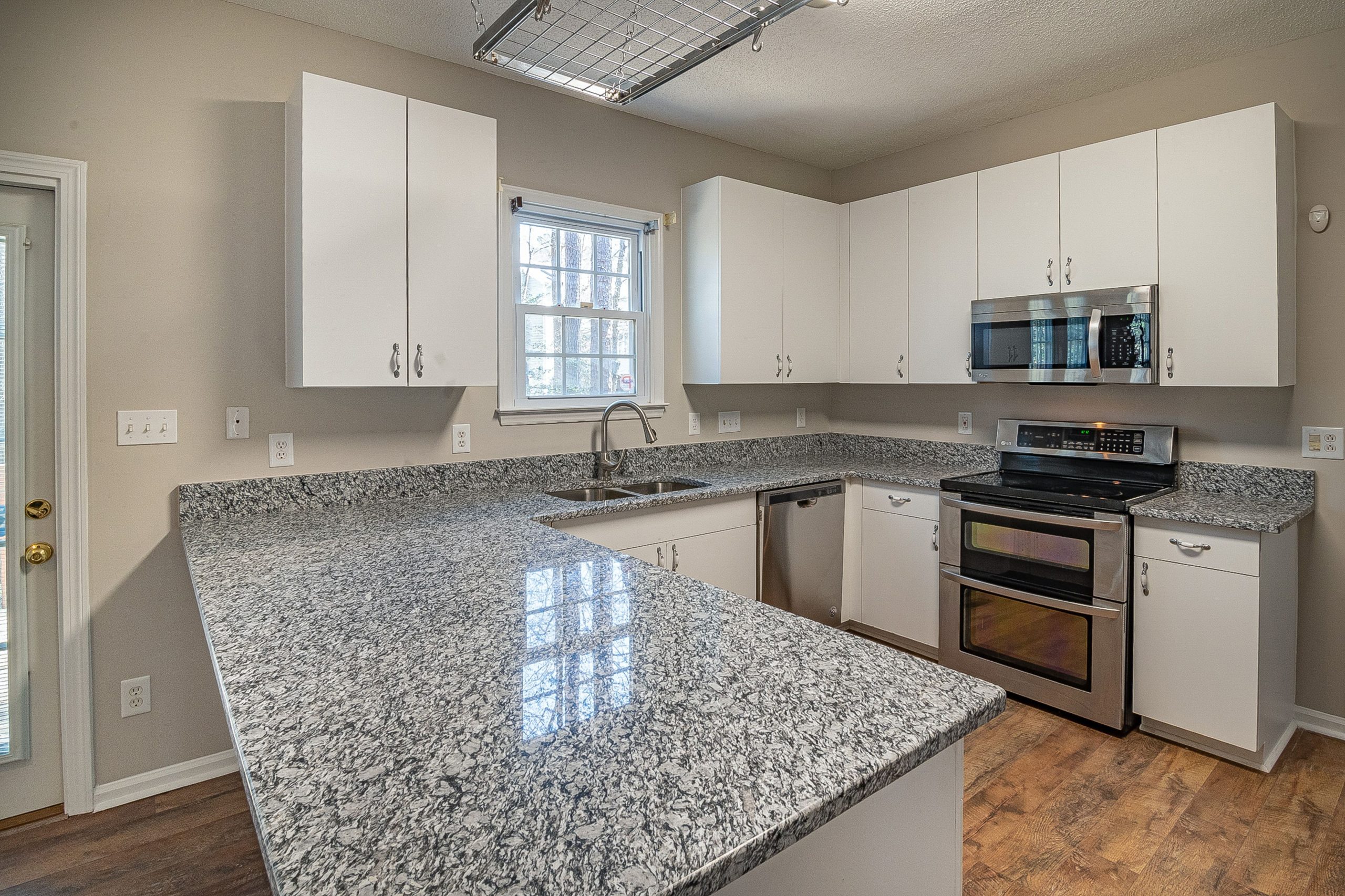 Sleek kitchen design featuring granite countertops, white cabinets, and stainless steel appliances.