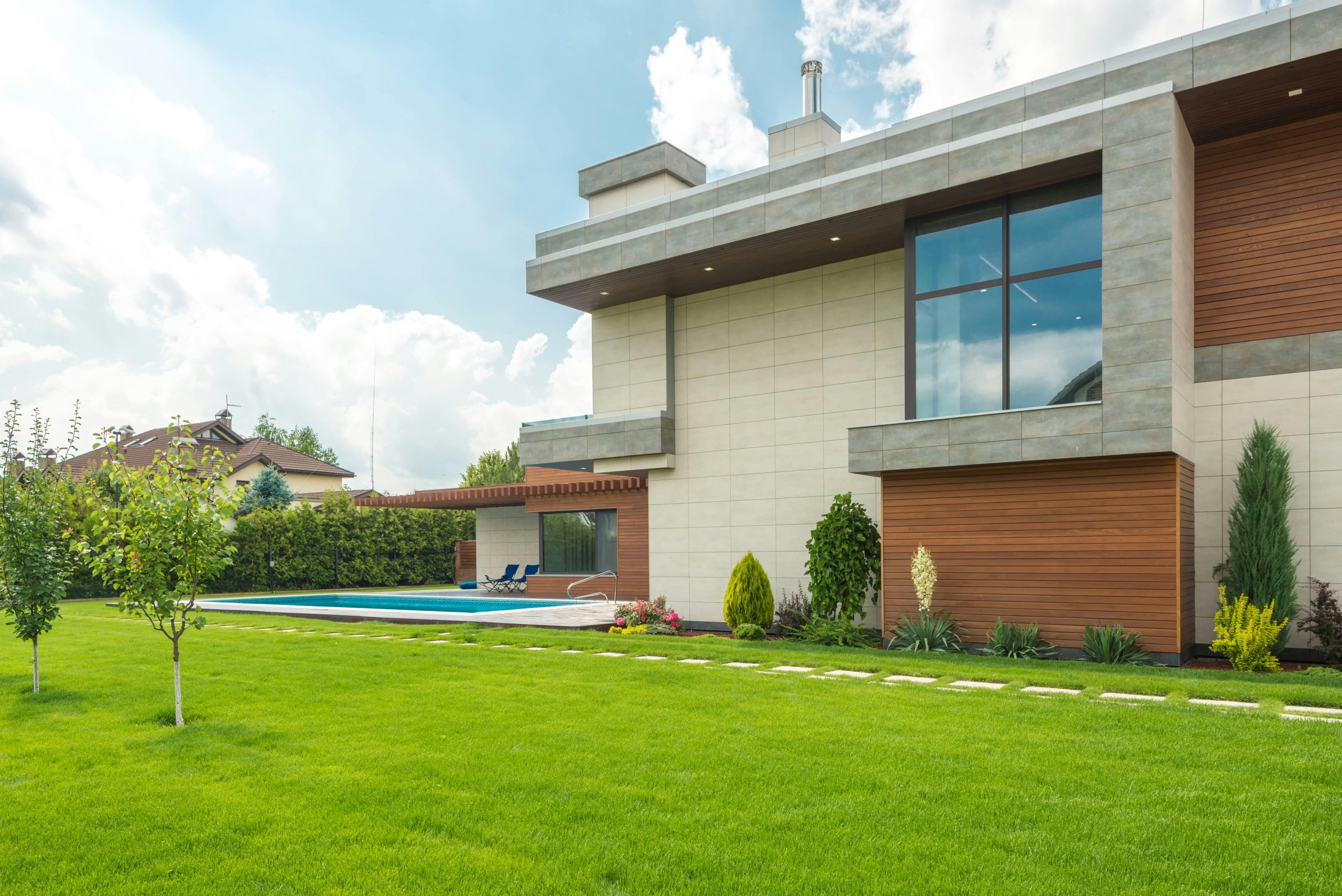 Sleek modern house with swimming pool and lush lawn, perfect for luxury living.