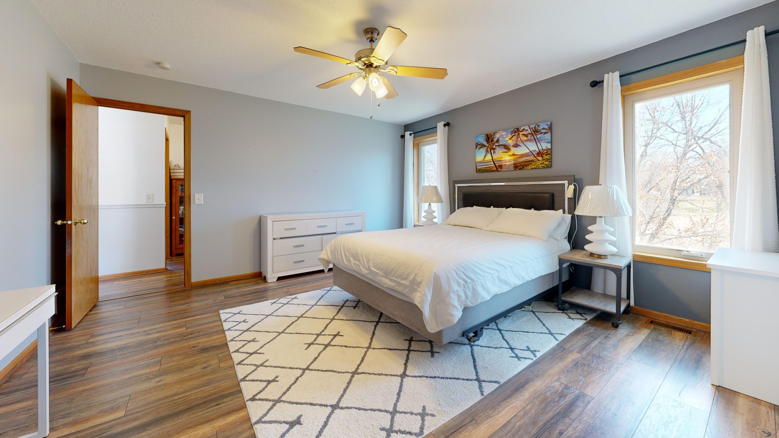 Spacious bedroom with neutral decor and wooden flooring, highlighting comfort and modern elegance.
