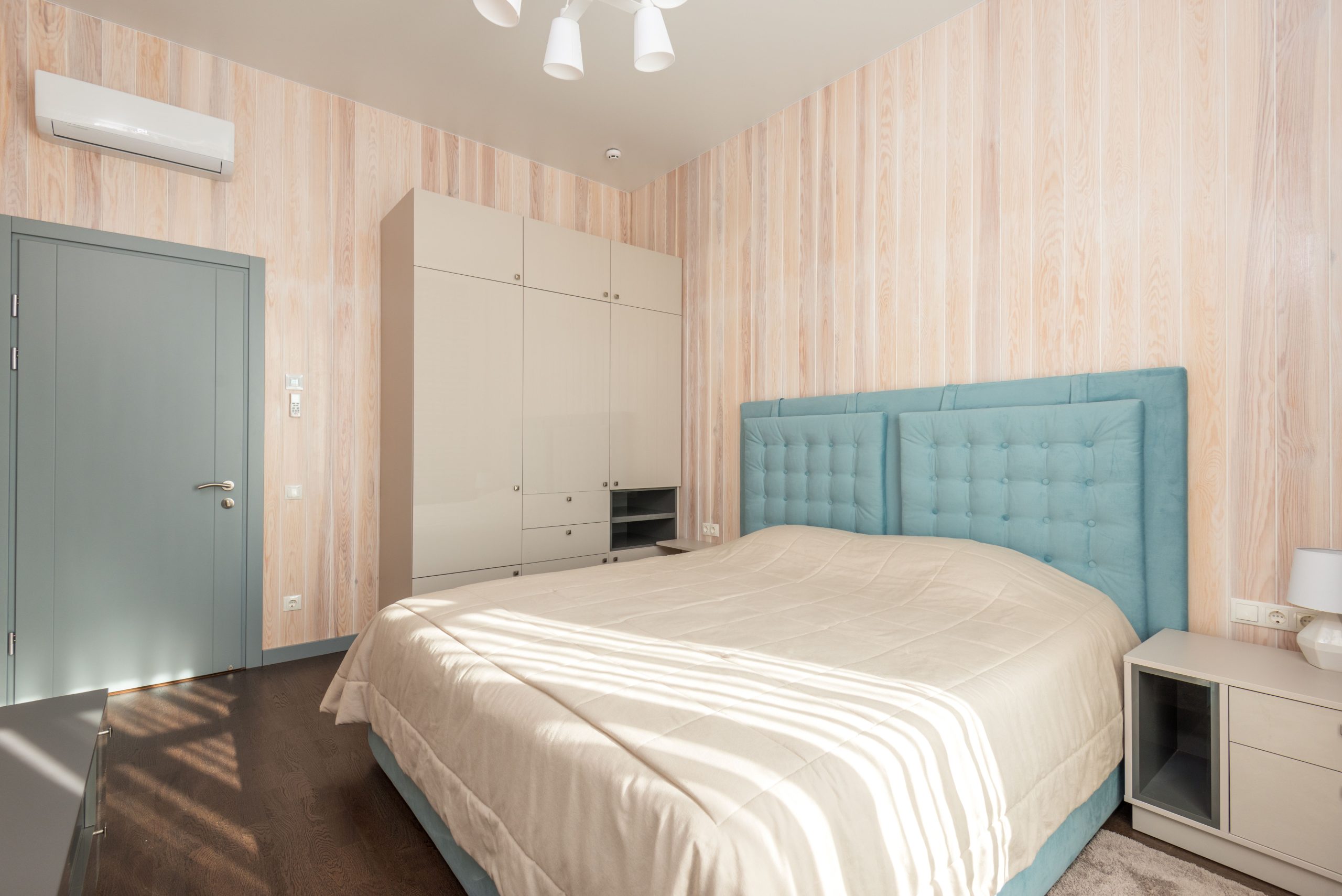 Spacious bedroom with teal accents and modern furnishings for a cozy atmosphere.