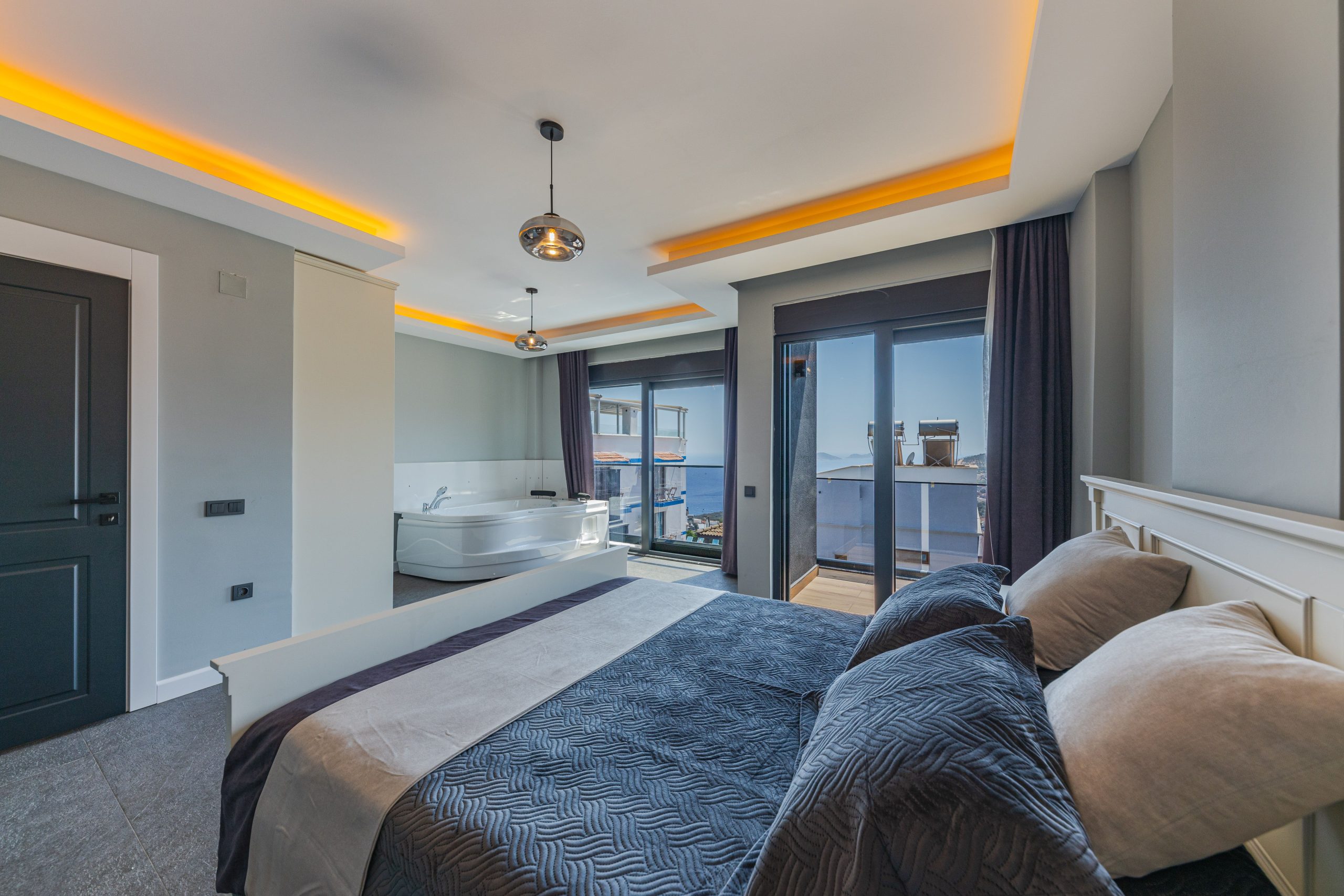 Spacious contemporary bedroom featuring luxury decor and ocean view through large windows.