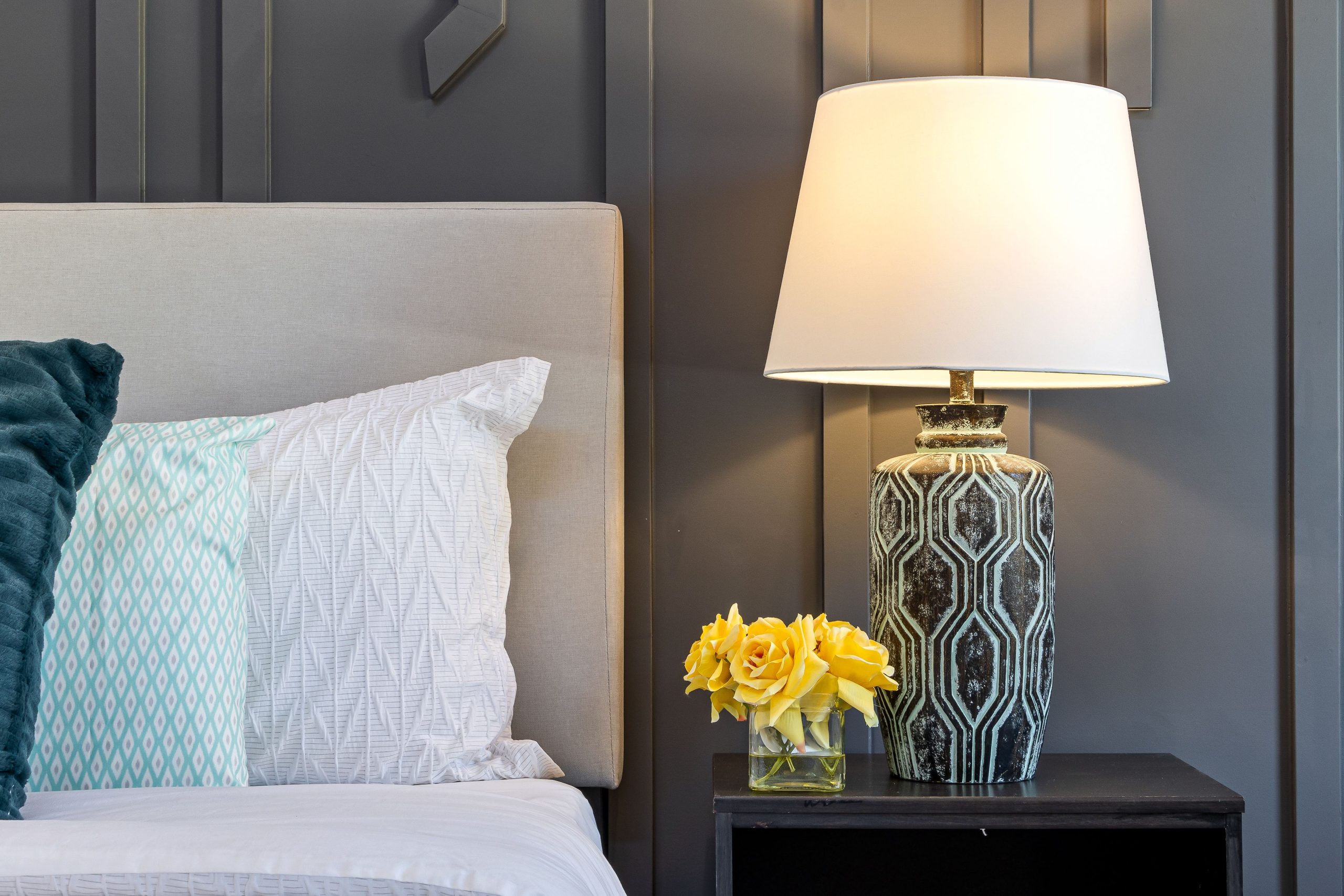 Stylish bedroom featuring a decorative lamp, fresh flowers, and cozy pillows for a modern interior look.