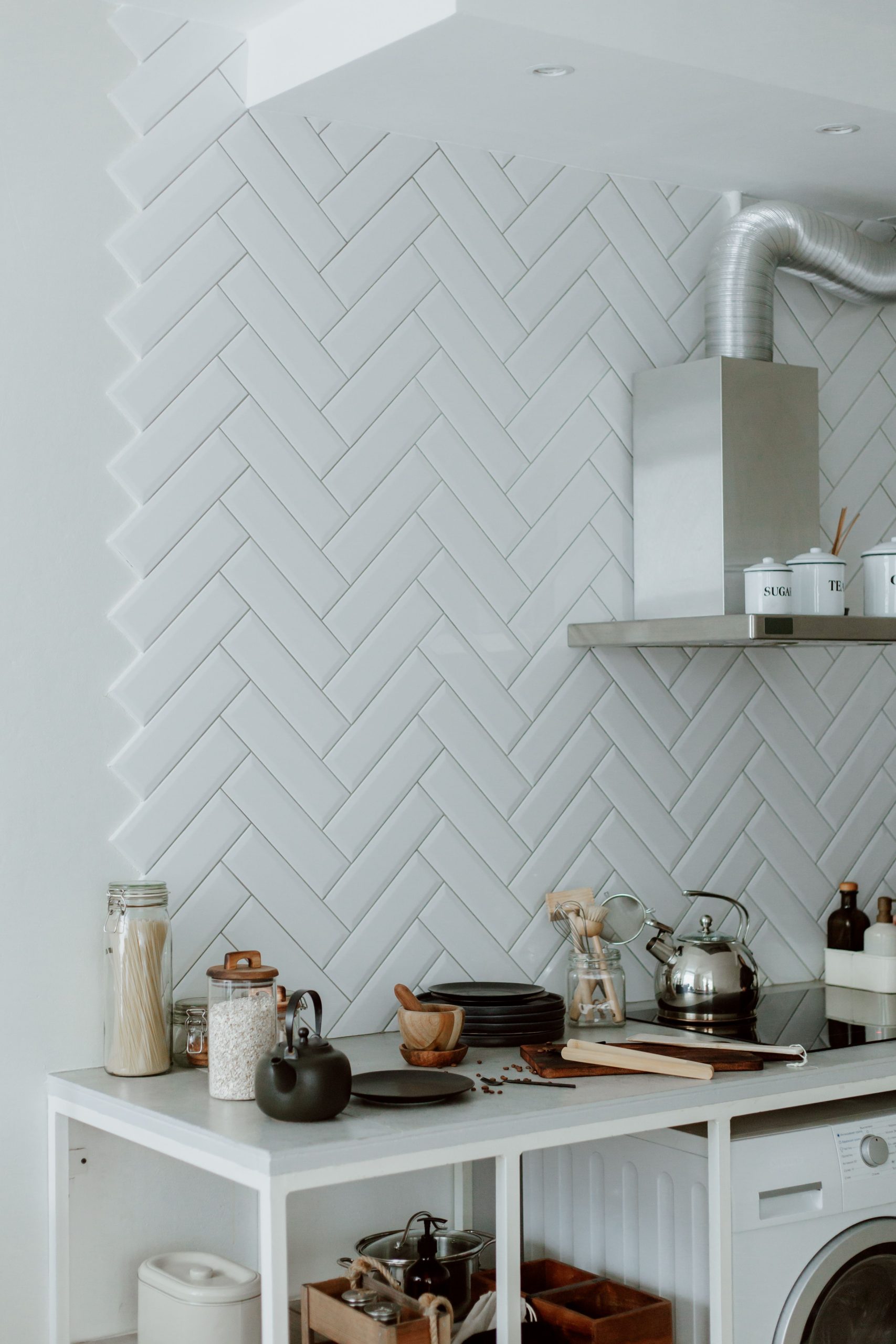 Stylish kitchen with modern appliances, utensils, and a herringbone backsplash.