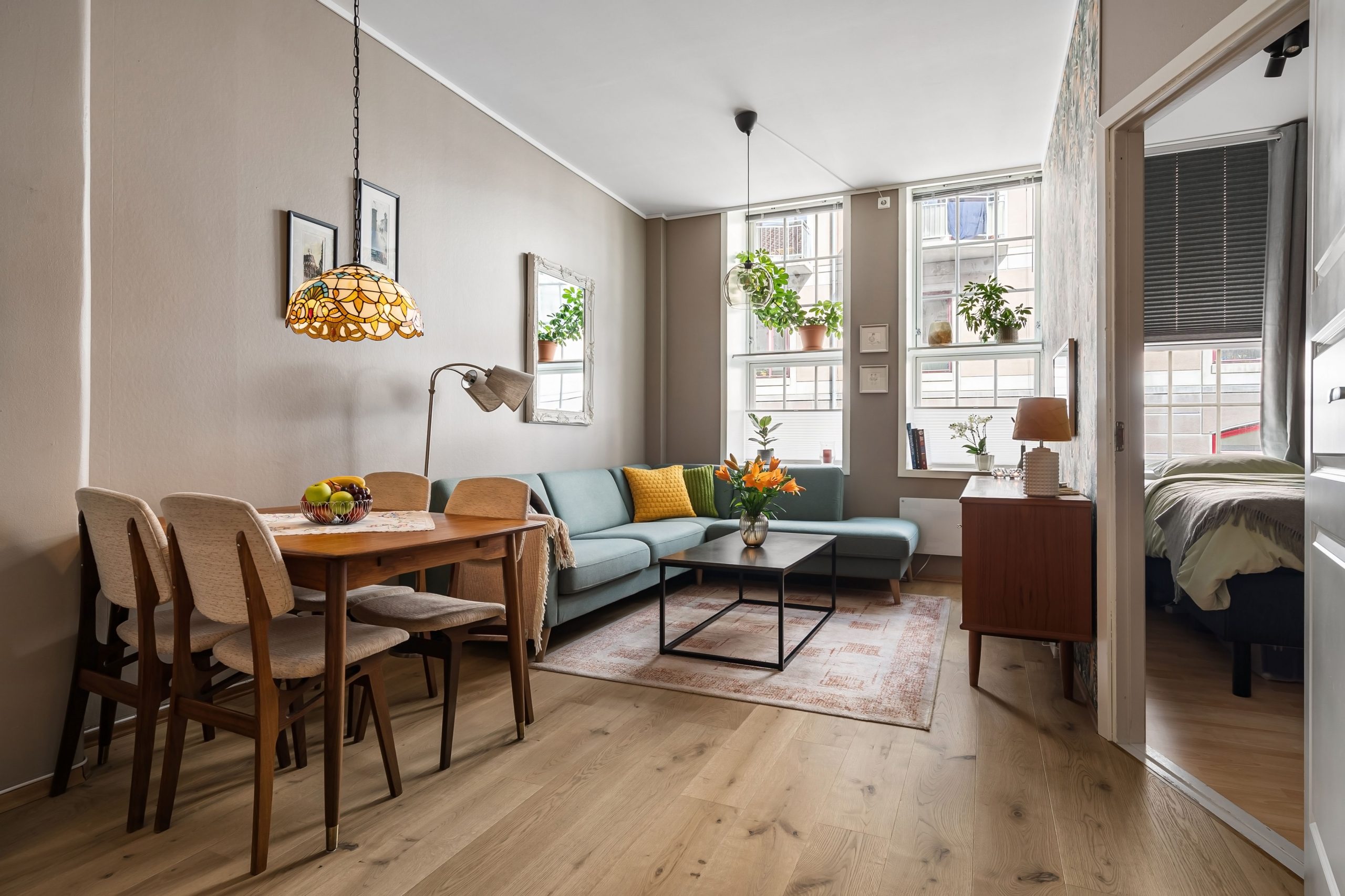 Stylish living room with dining area, wooden furniture, and indoor plants, creating a cozy atmosphere.