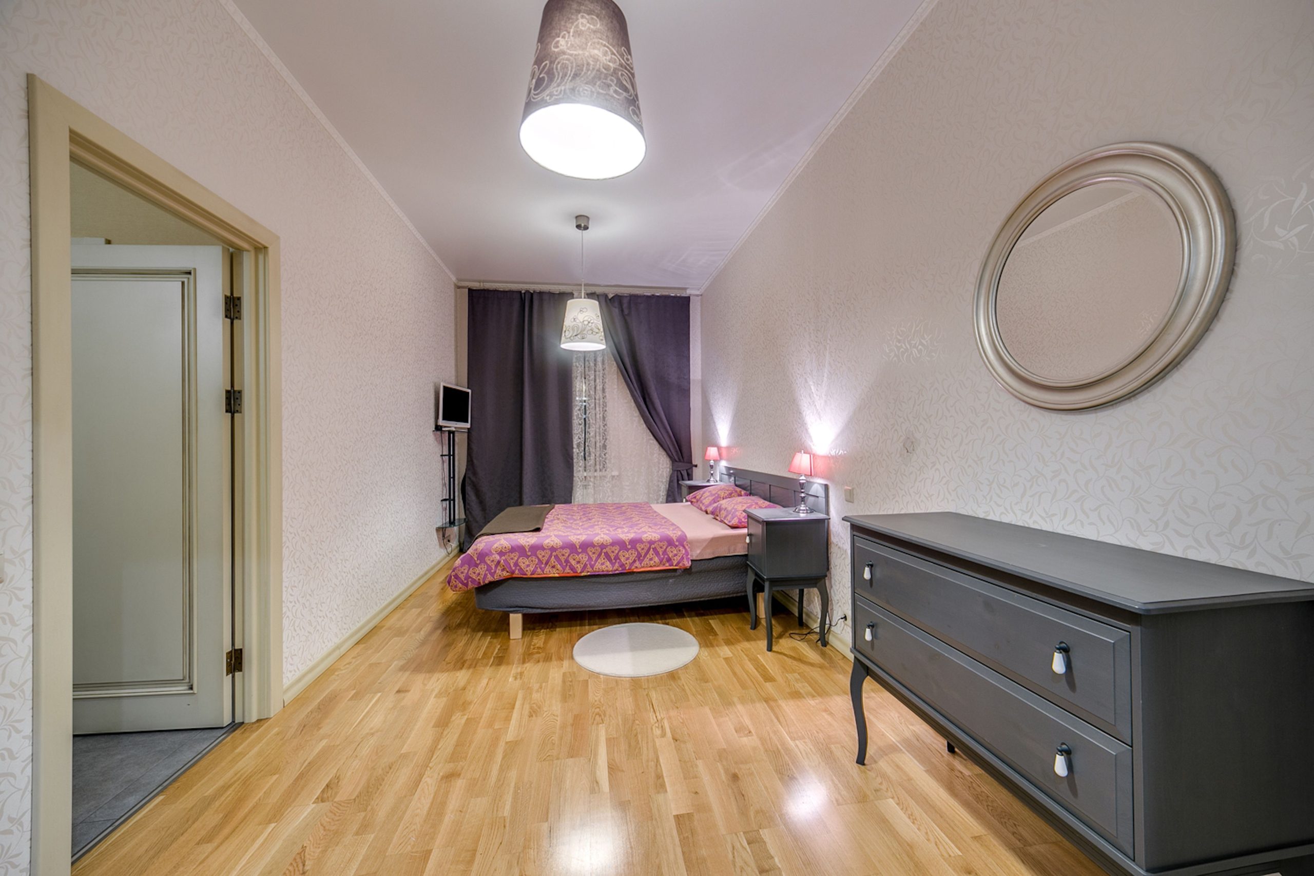 Stylish modern bedroom with wooden flooring and elegant furnishings.