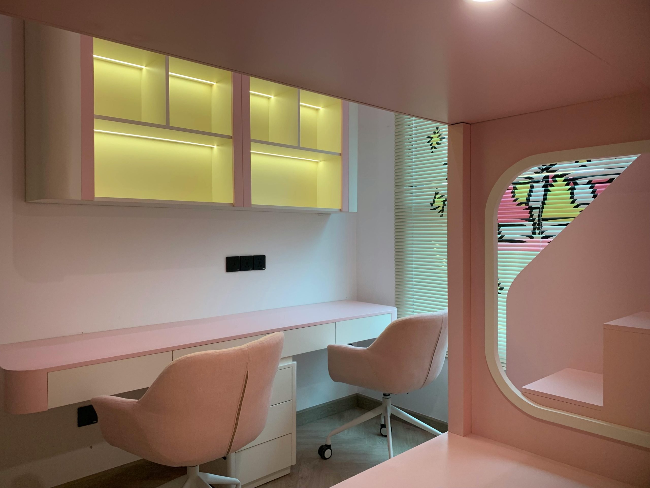 Stylish pink office space featuring sleek furniture and contemporary design with soft lighting.