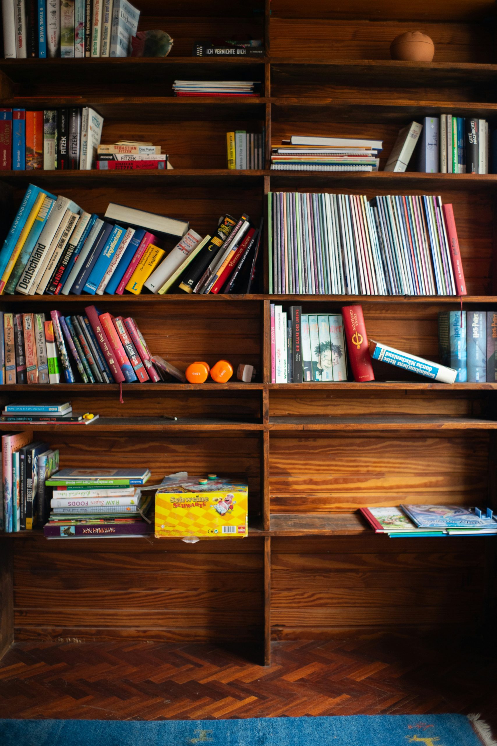 The image showcases a bookshelf brimming with a variety of books atop a wooden floor, highlighting a cozy and inviting reading space. The arrangement of books adds character and warmth to the room, su