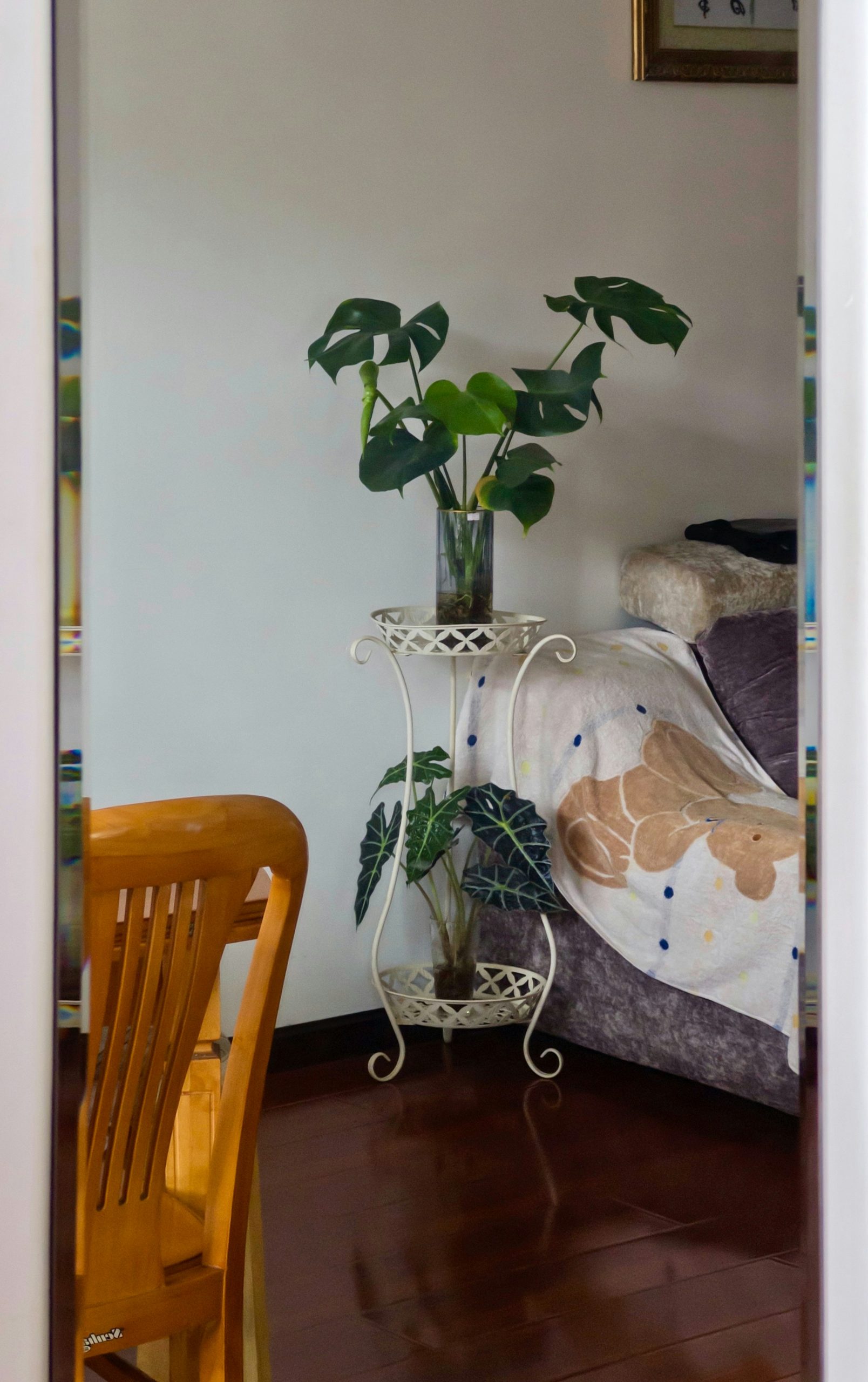 Two potted plants on a stand next to a couch.