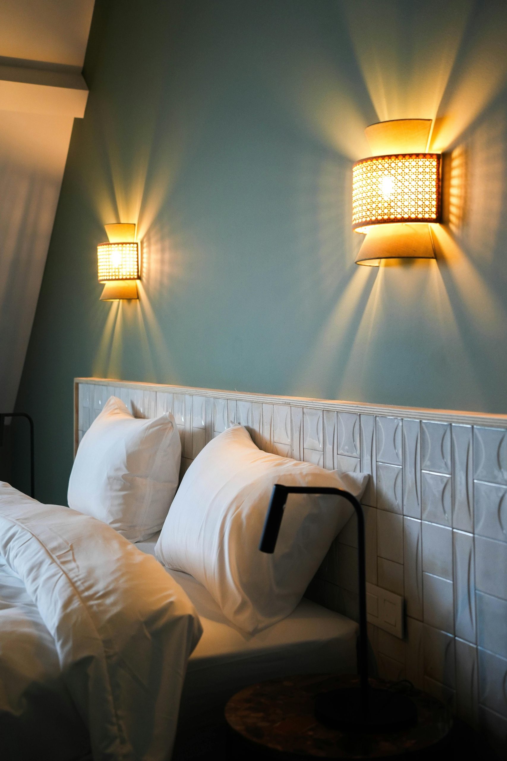 Warm and inviting bedroom illuminated by stylish wall sconces, perfect for relaxation.