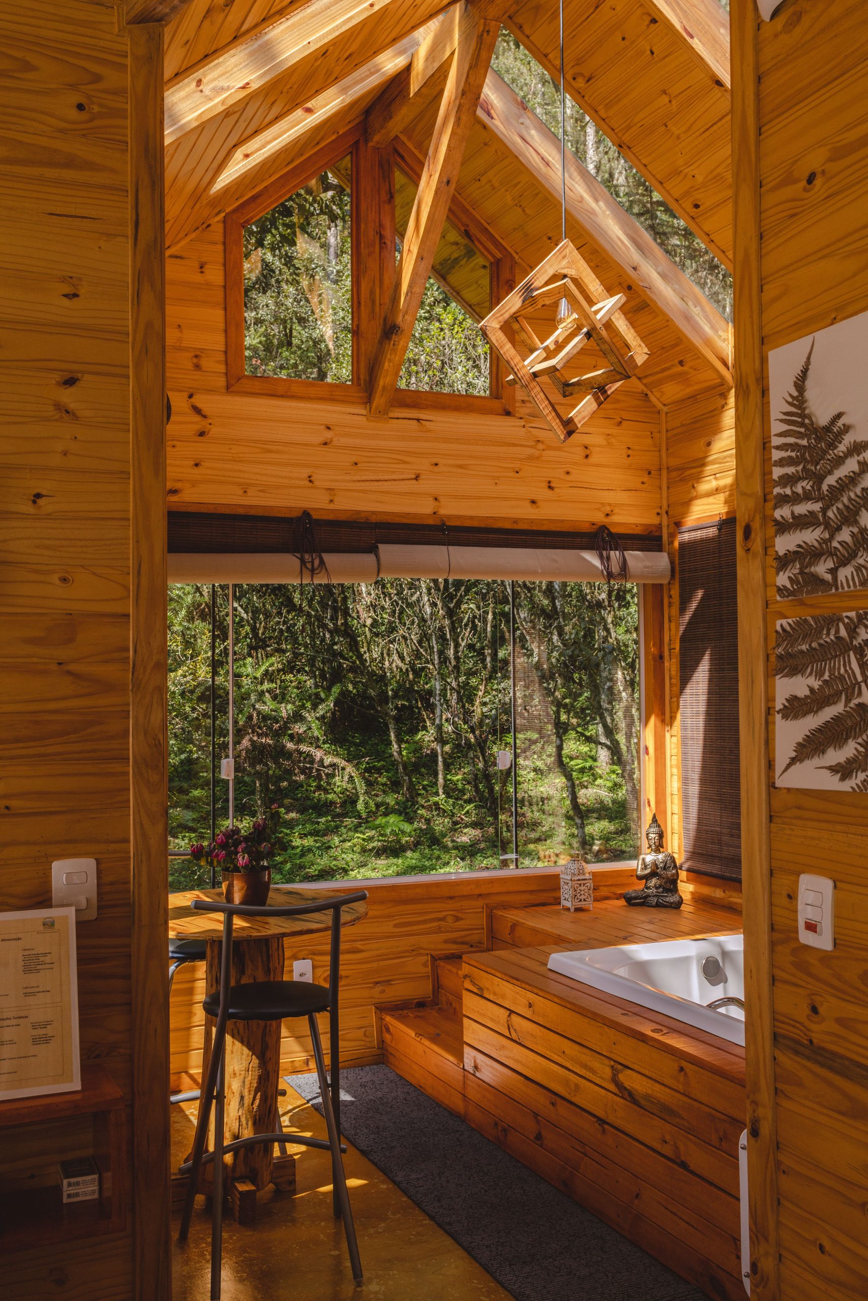Warm wooden cabin interior with a serene forest view and natural lighting.