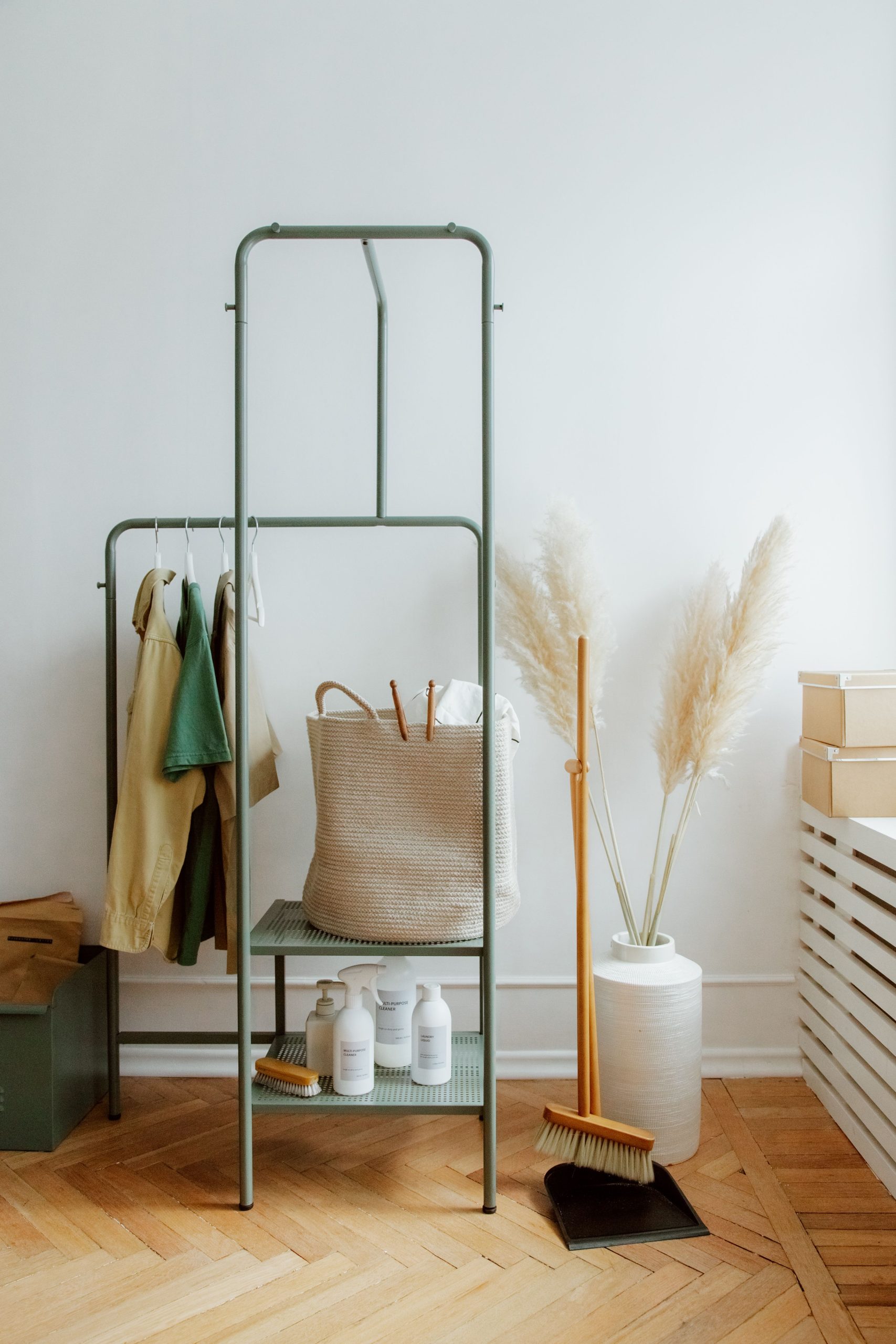 A chic corner featuring a minimalist clothing rack and cleaning essentials.