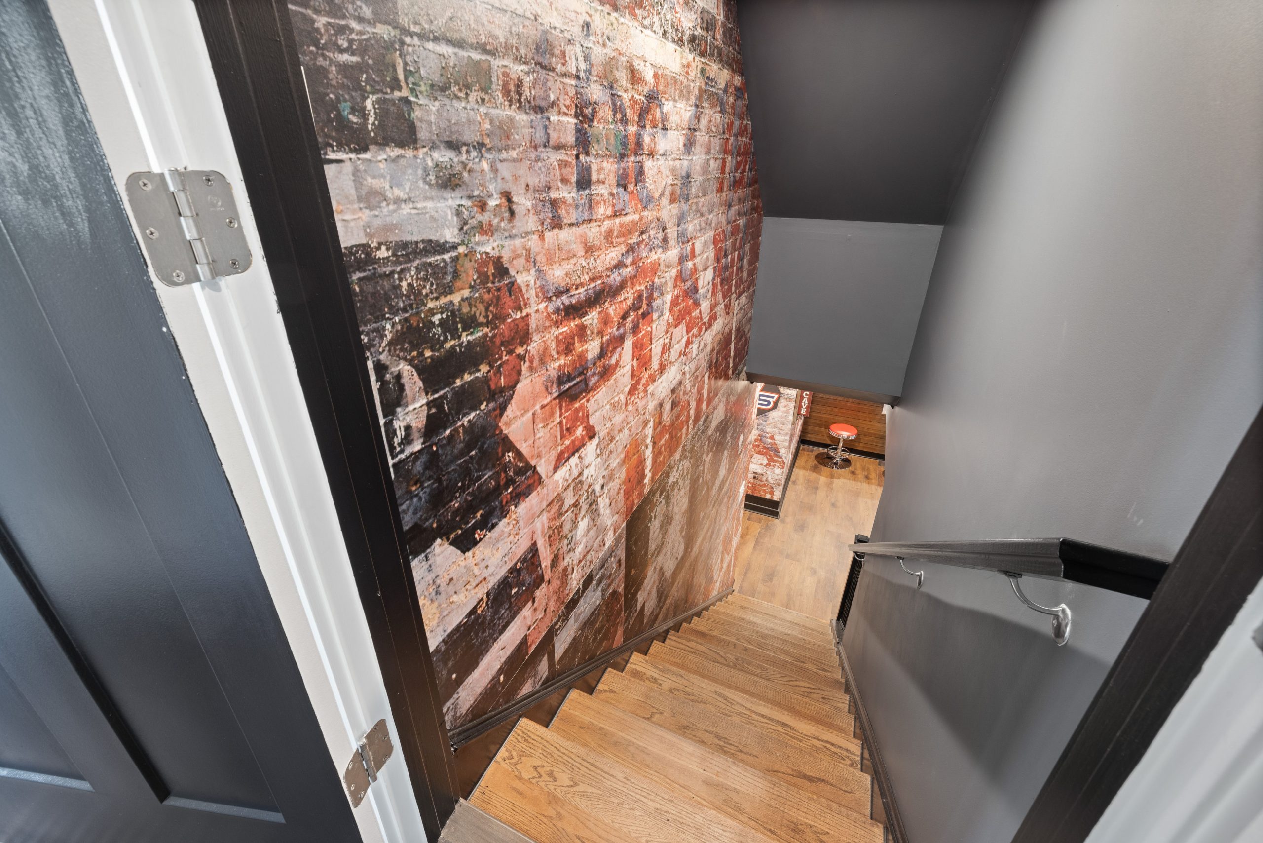 A modern staircase with exposed brick wall art leading to a stylish basement.