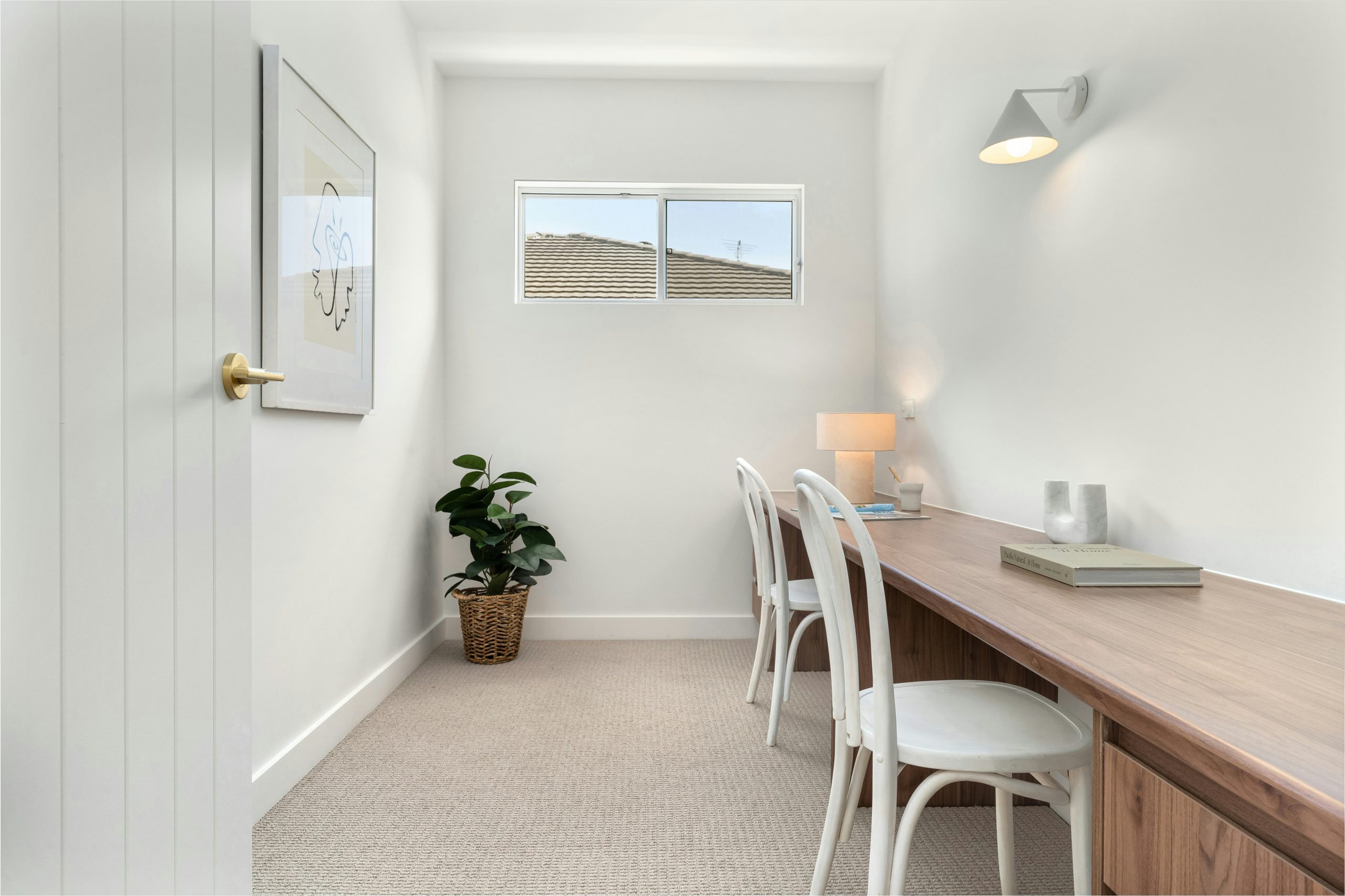 A room with a desk and chairs and a potted plant