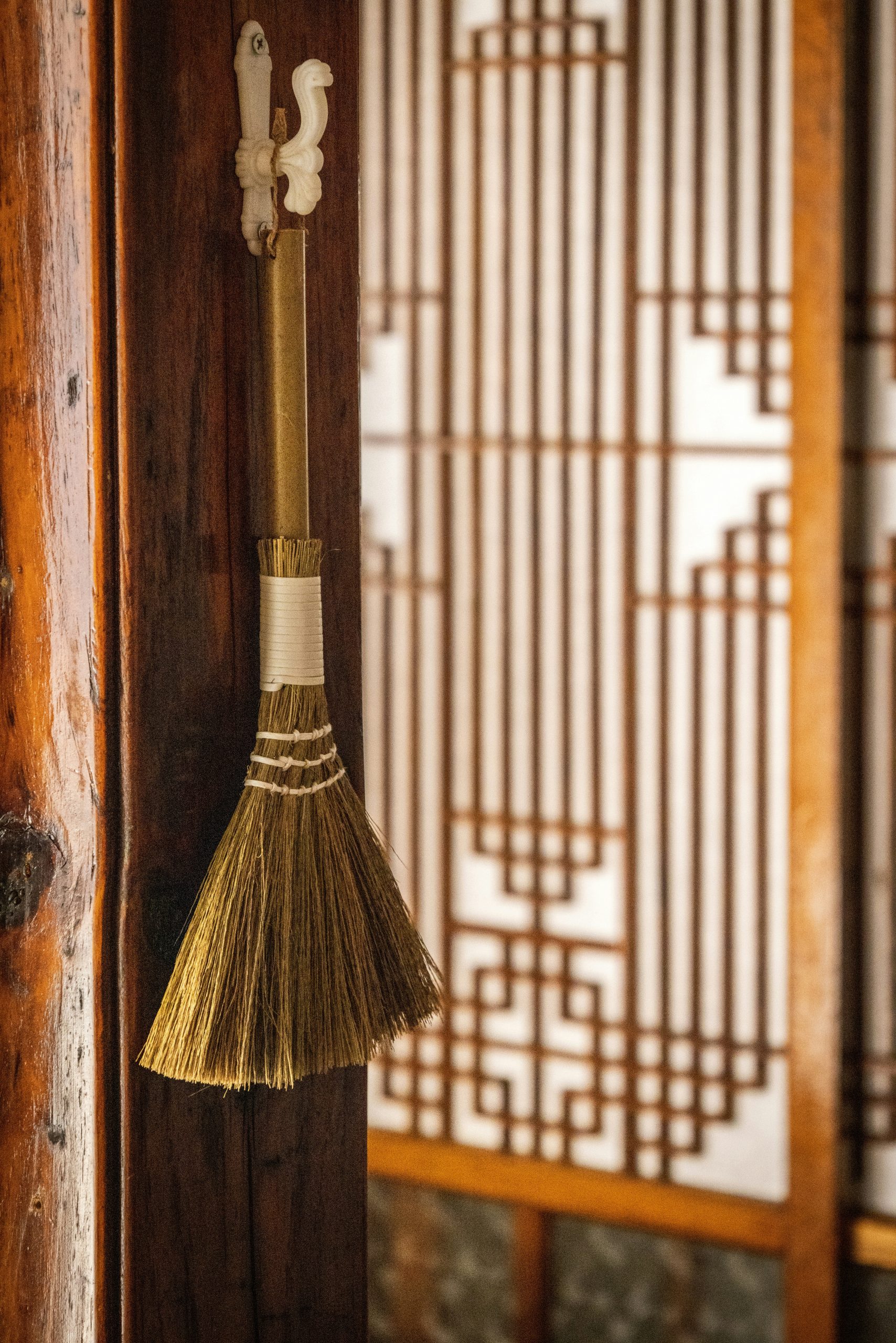 A small straw broom hangs in a hanok, a traditional Korean house.