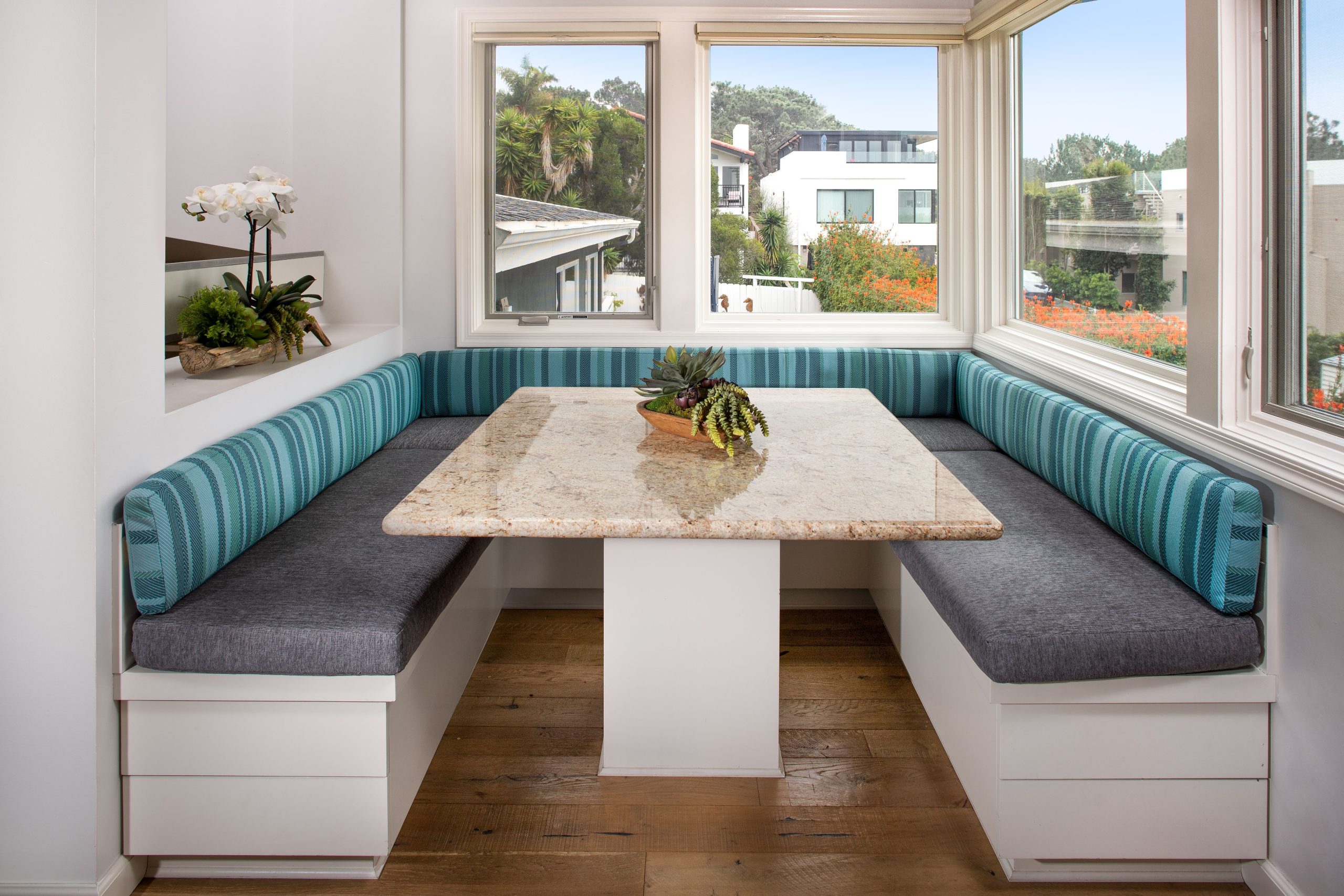 A stylish dining nook with a granite table in a bright San Diego home, featuring a coastal view.