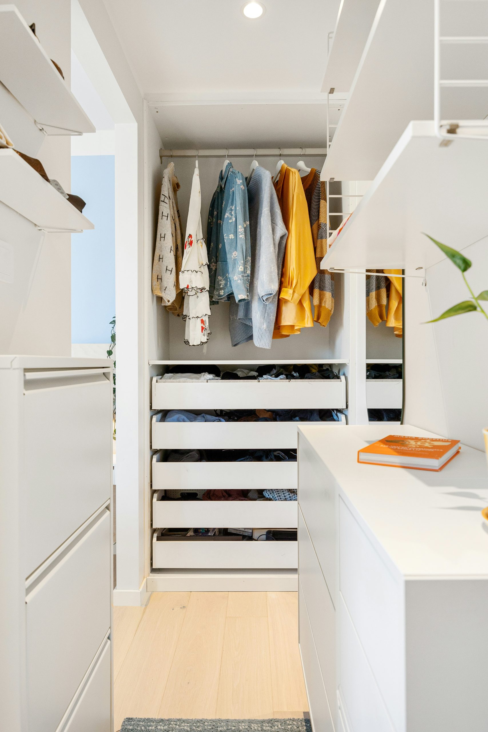 A walk in closet with white cabinets and drawers
