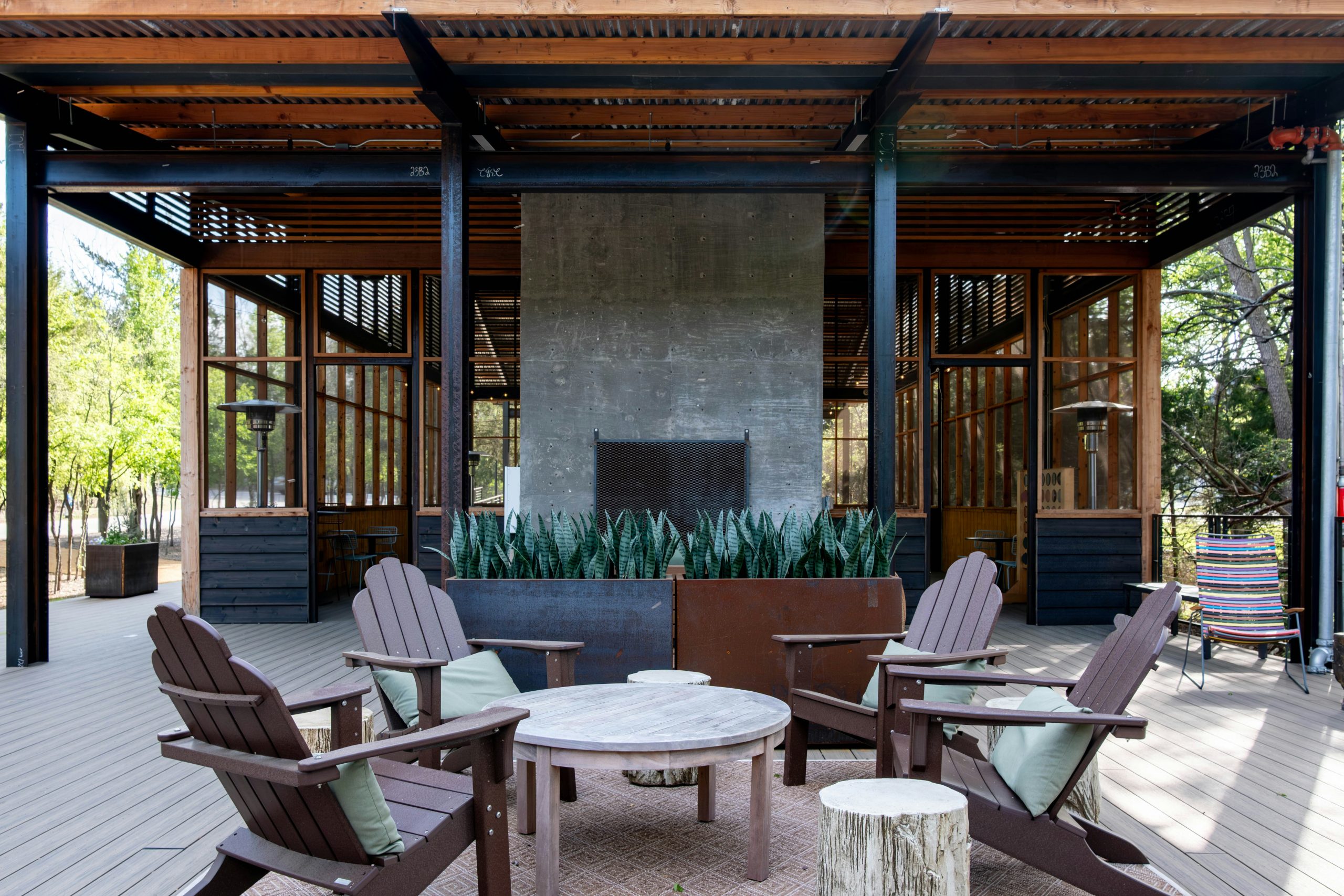 An outdoor patio with a fireplace and adirondack chairs.