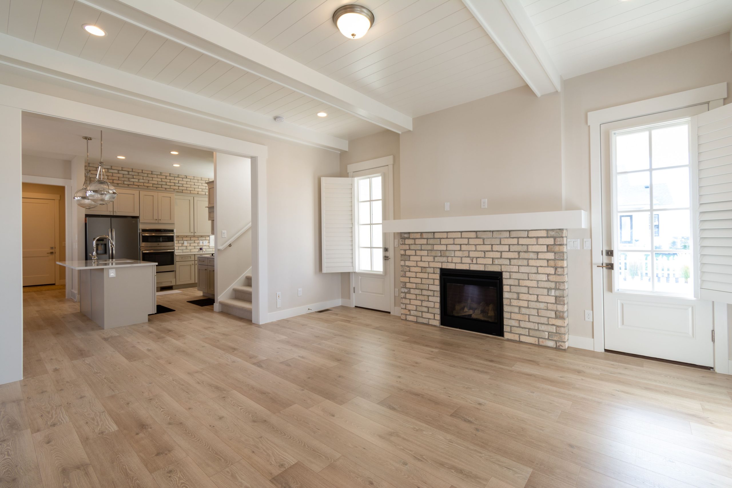Bright and airy modern living space featuring a brick fireplace and open kitchen design.