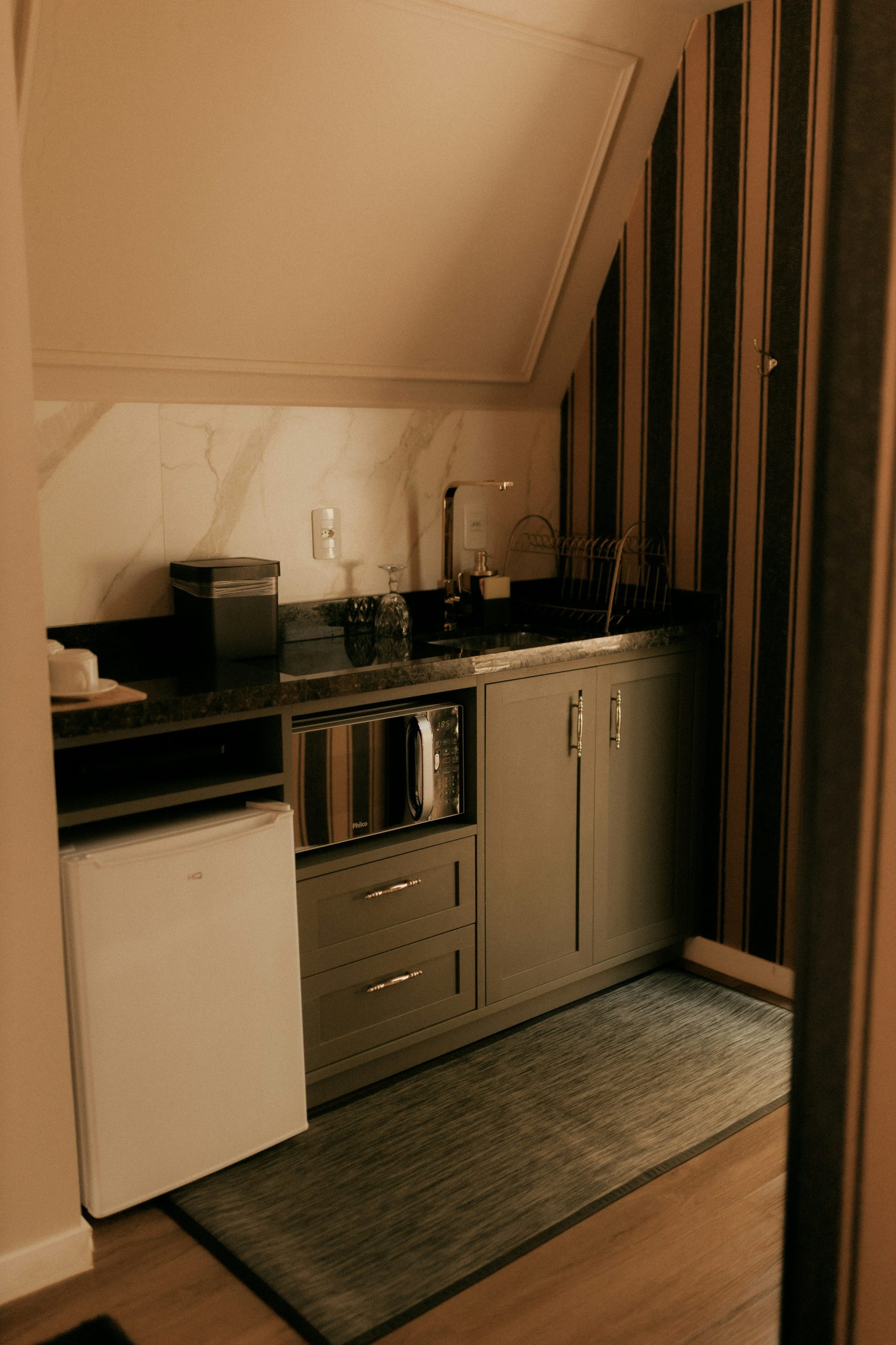 Compact kitchen with microwave, mini-fridge, and sink.