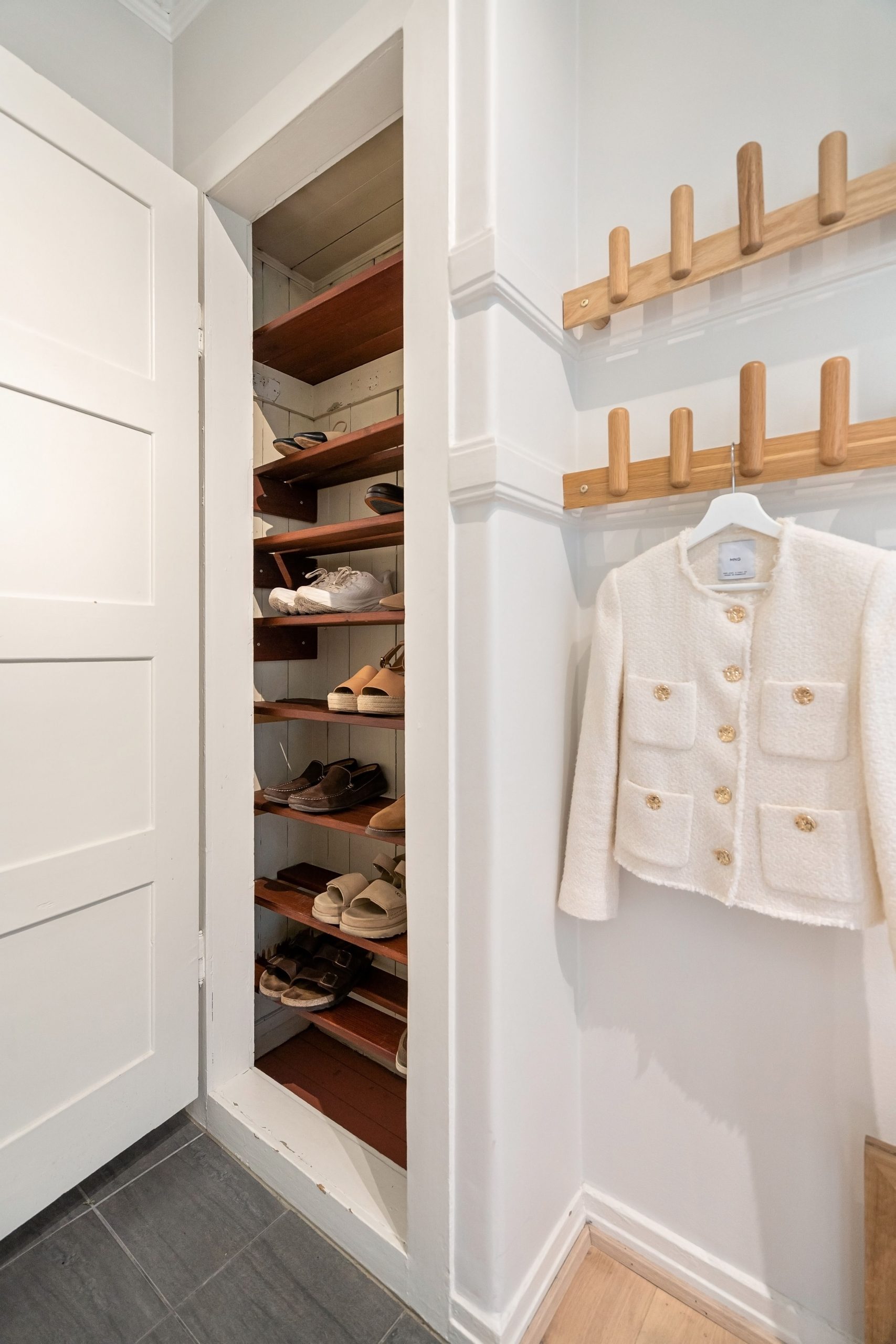 Contemporary closet scene with organized shoe storage and elegant coat rack.