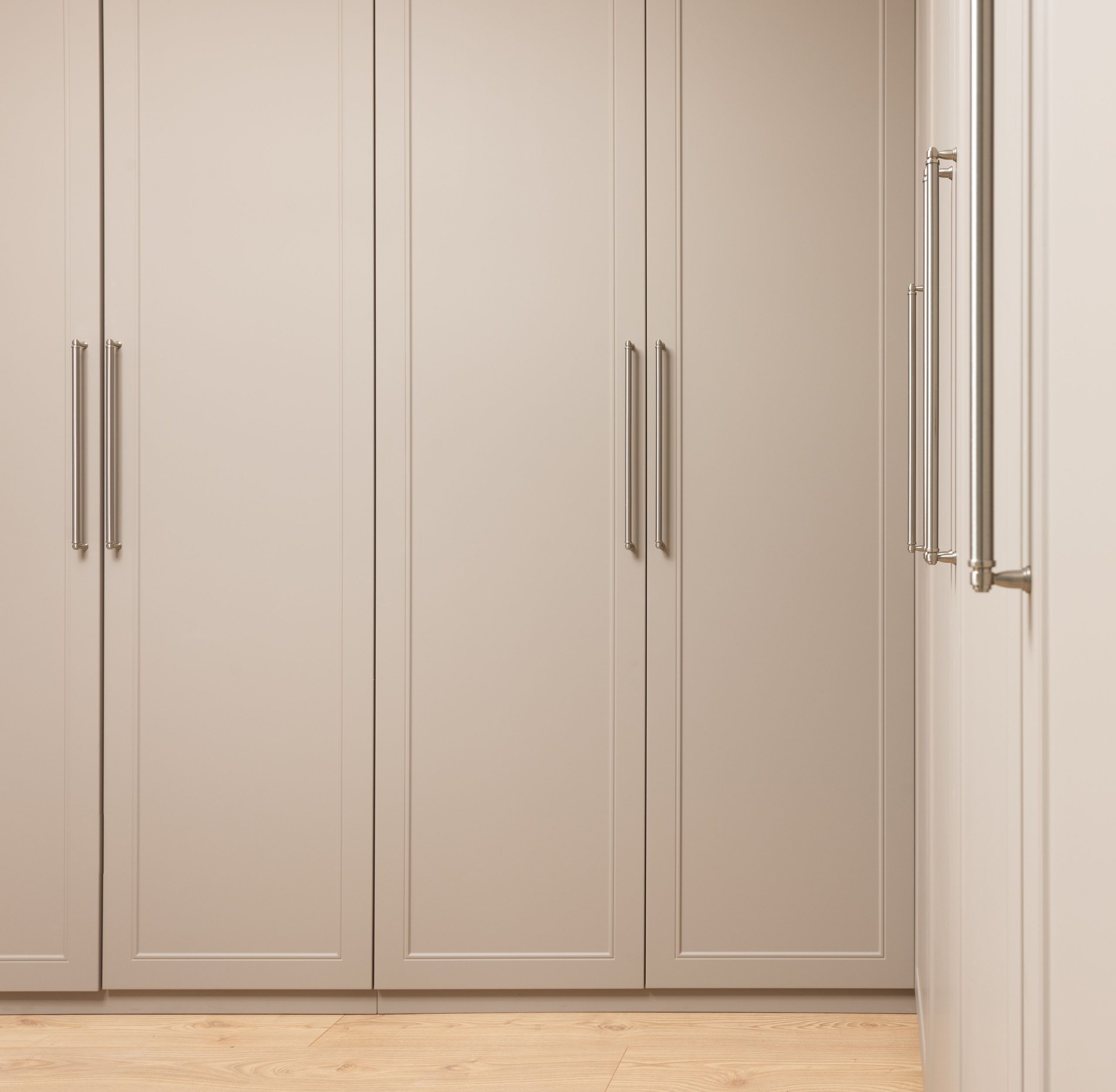 Contemporary closet with beige doors and metal handles above floor in modern light house